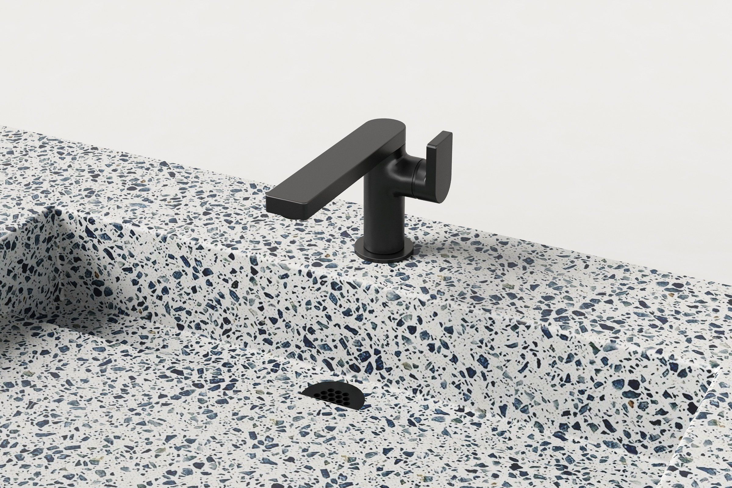 Close-up of matte black faucet and integrated drain on terrazzo double-basin sink.