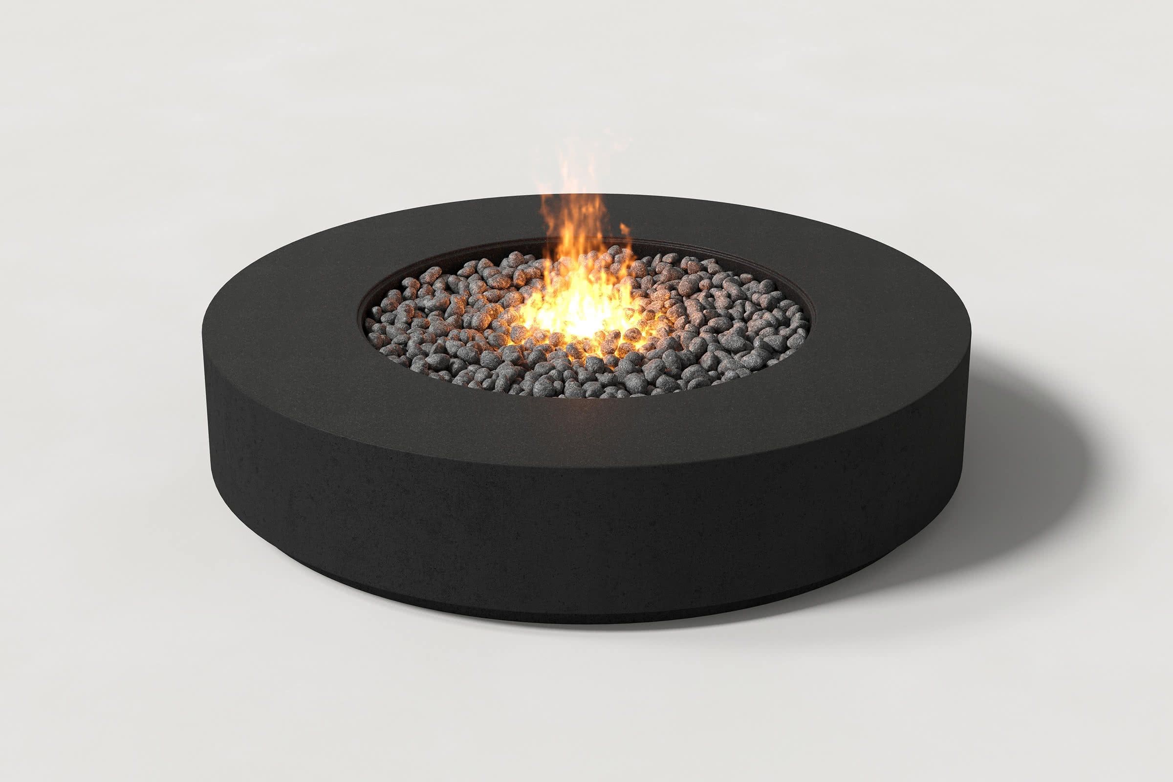 Low cylindrical jet black concrete fire pit with thick walls and central circular well. Mid-range angle shows well filled with flaming volcanic rocks on a white background.