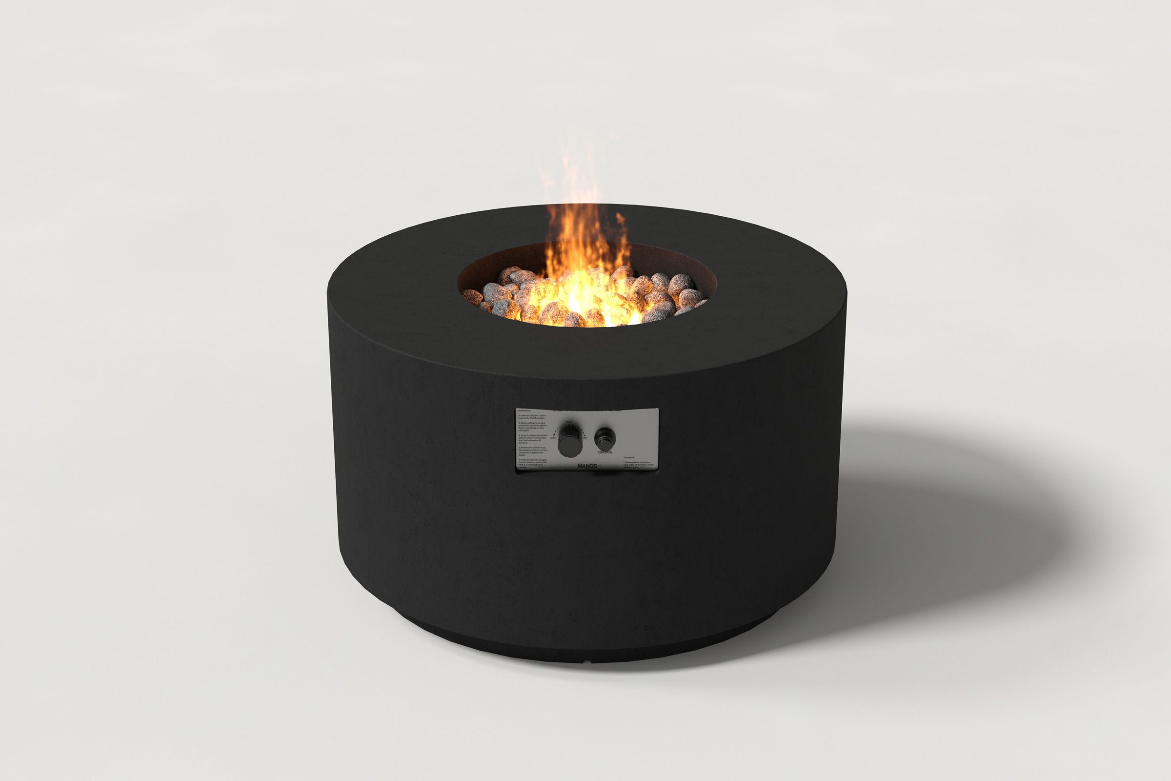 Low cylindrical black colored concrete fire pit with thick walls and a central circular well filled with dark volcanic rocks and flame. Side view on a white background.