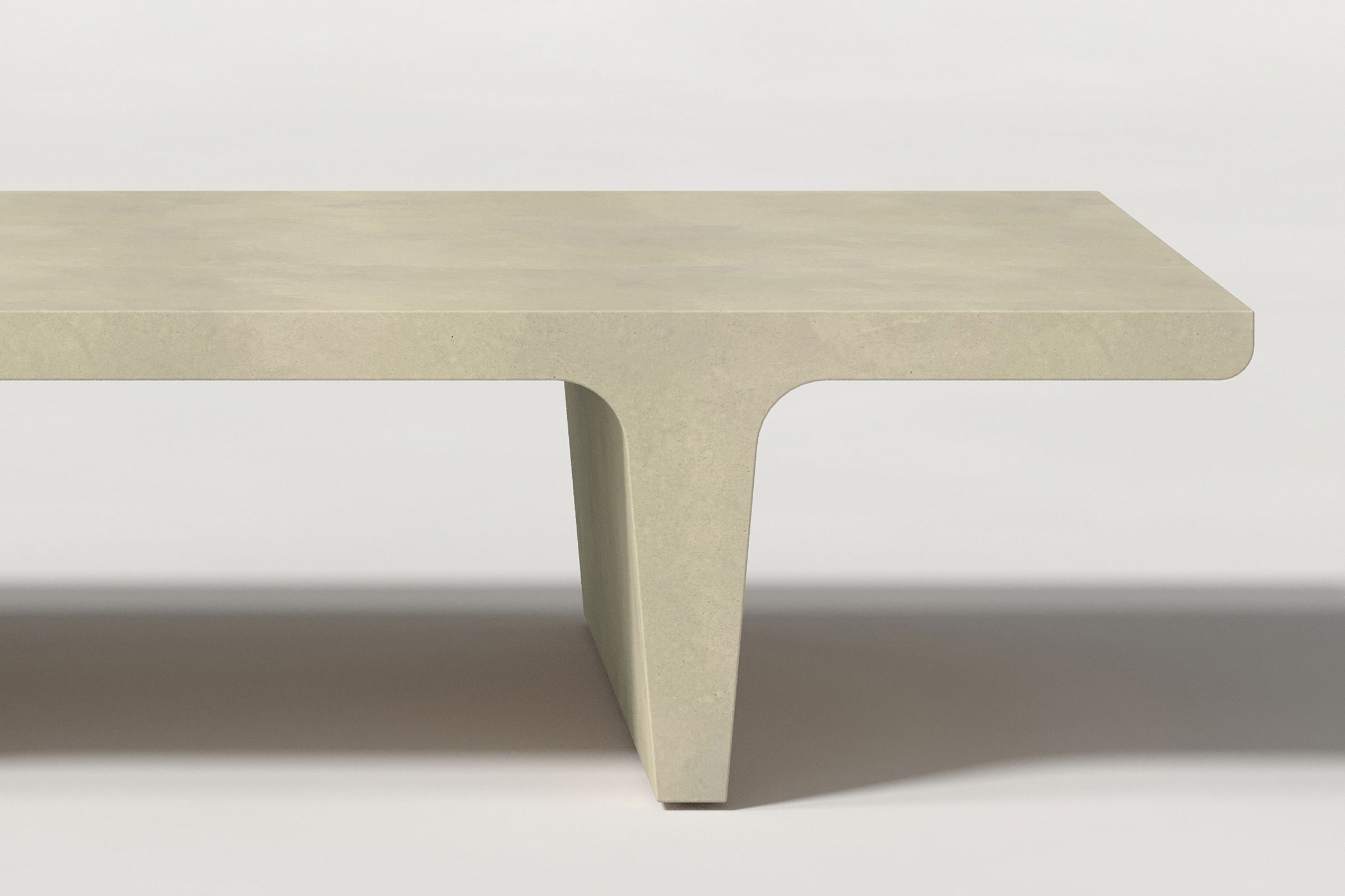 Close-up of a light beige concrete coffee table with sculptural double tee legs, highlighting soft edges and subtle surface texture against a clean white background.