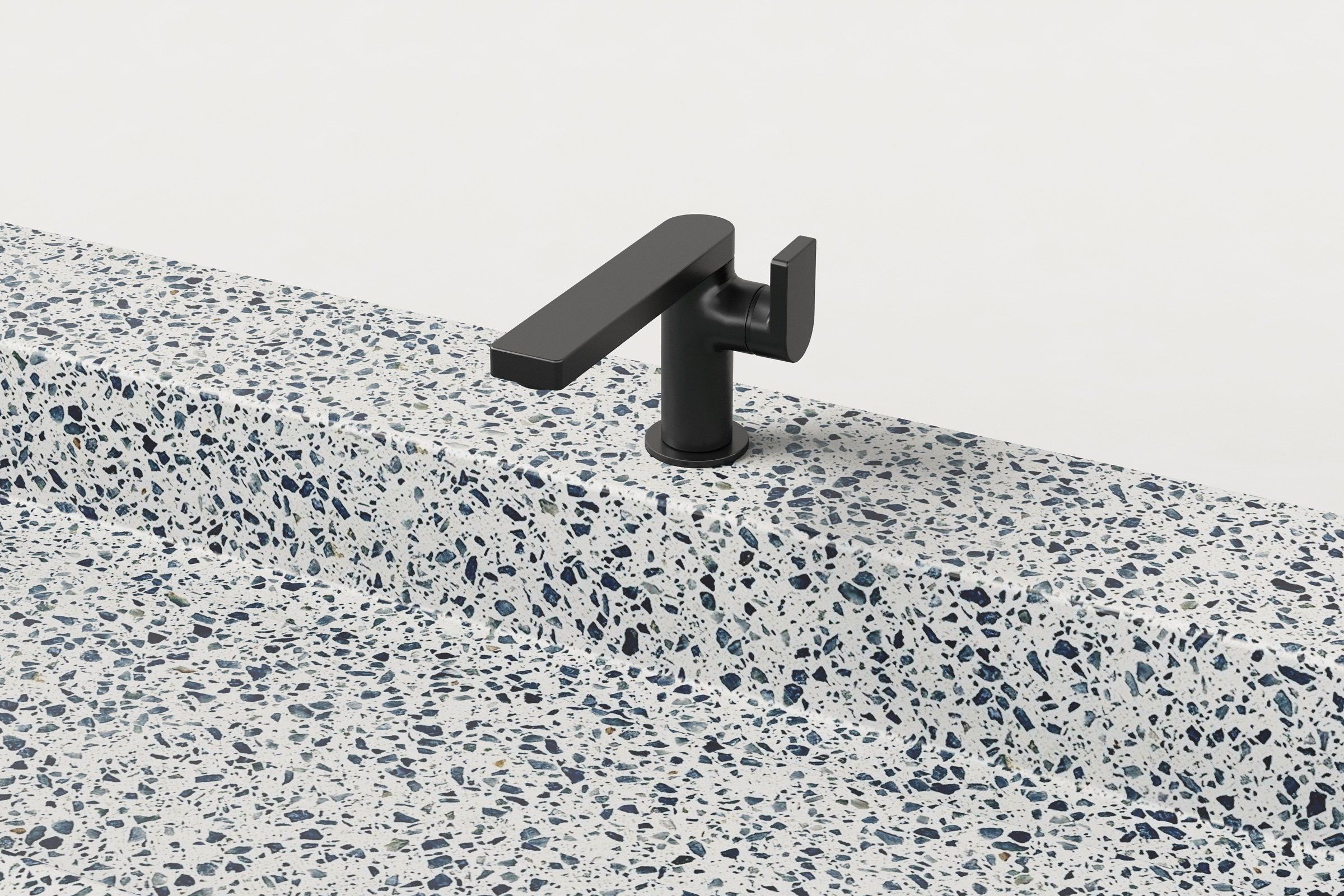 Close-up of matte black faucet mounted on terrazzo sink ledge.