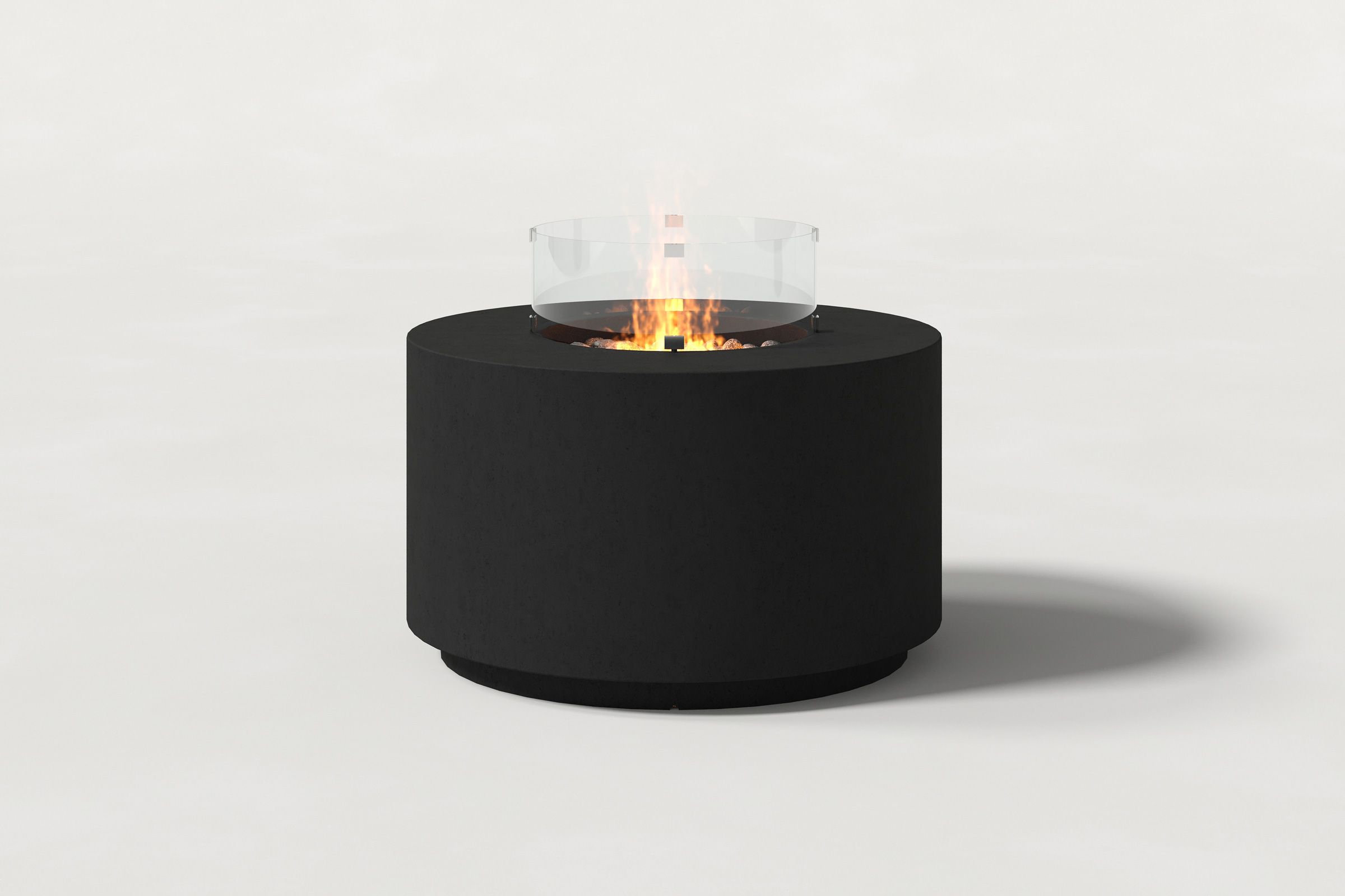 Low cylindrical black colored concrete fire pit with thick walls and a central circular well filled with dark volcanic rocks and flame, featuring an integrated control panel and glass shield. Front view on a white background.