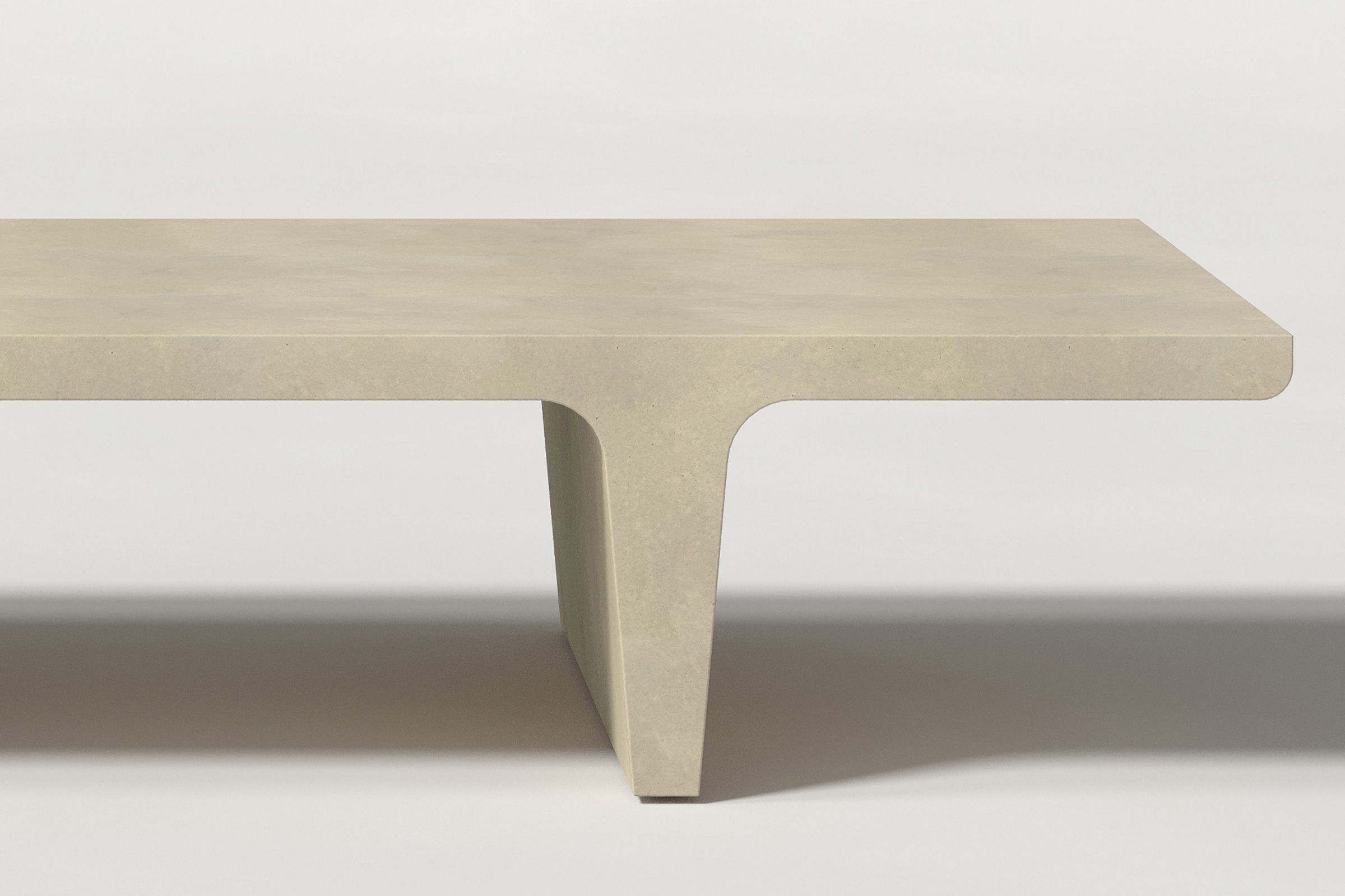 Close-up of a light beige concrete coffee table with sculptural double tee legs, highlighting soft edges and subtle surface texture against a clean white background.