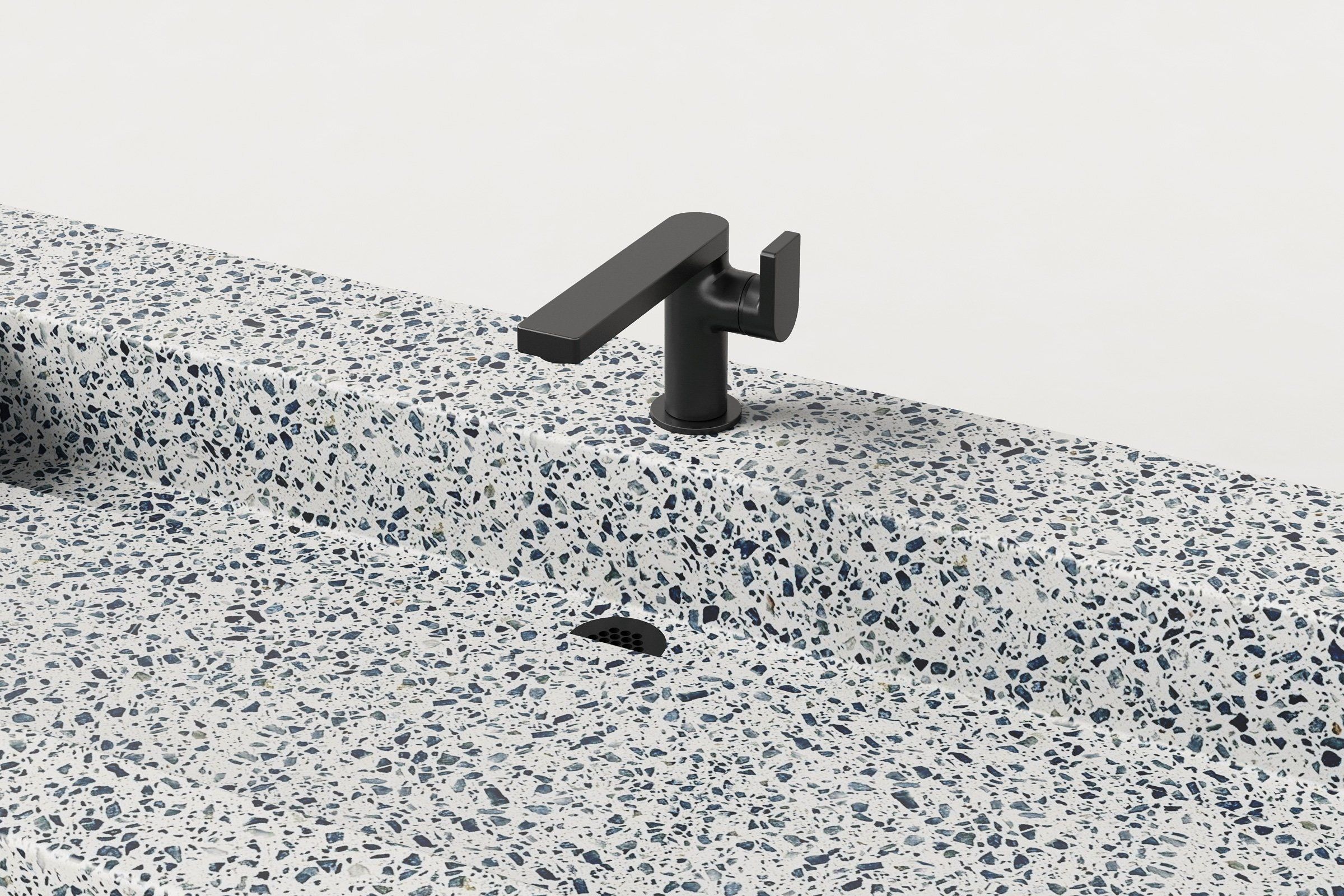 Close-up of Trof Drop 60 sink in Unazzo terrazzo finish, showing matte black faucet, integrated slope, and linear drain cover.