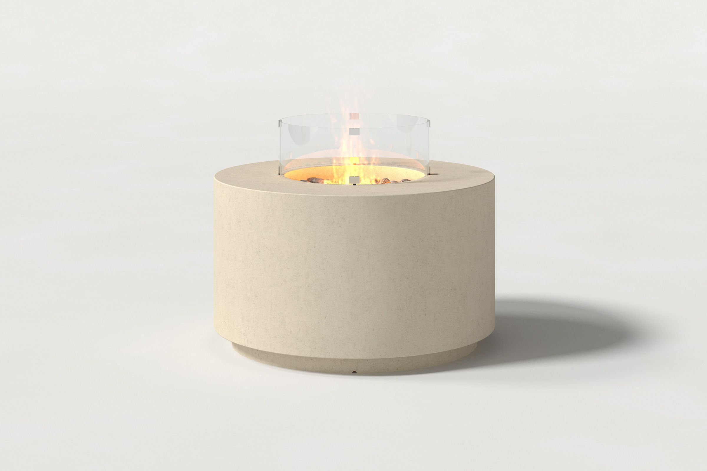 Low cylindrical sand-colored concrete fire pit with thick walls and a central circular well filled with dark volcanic rocks and flame, and glass shield. Front view on a white background.
