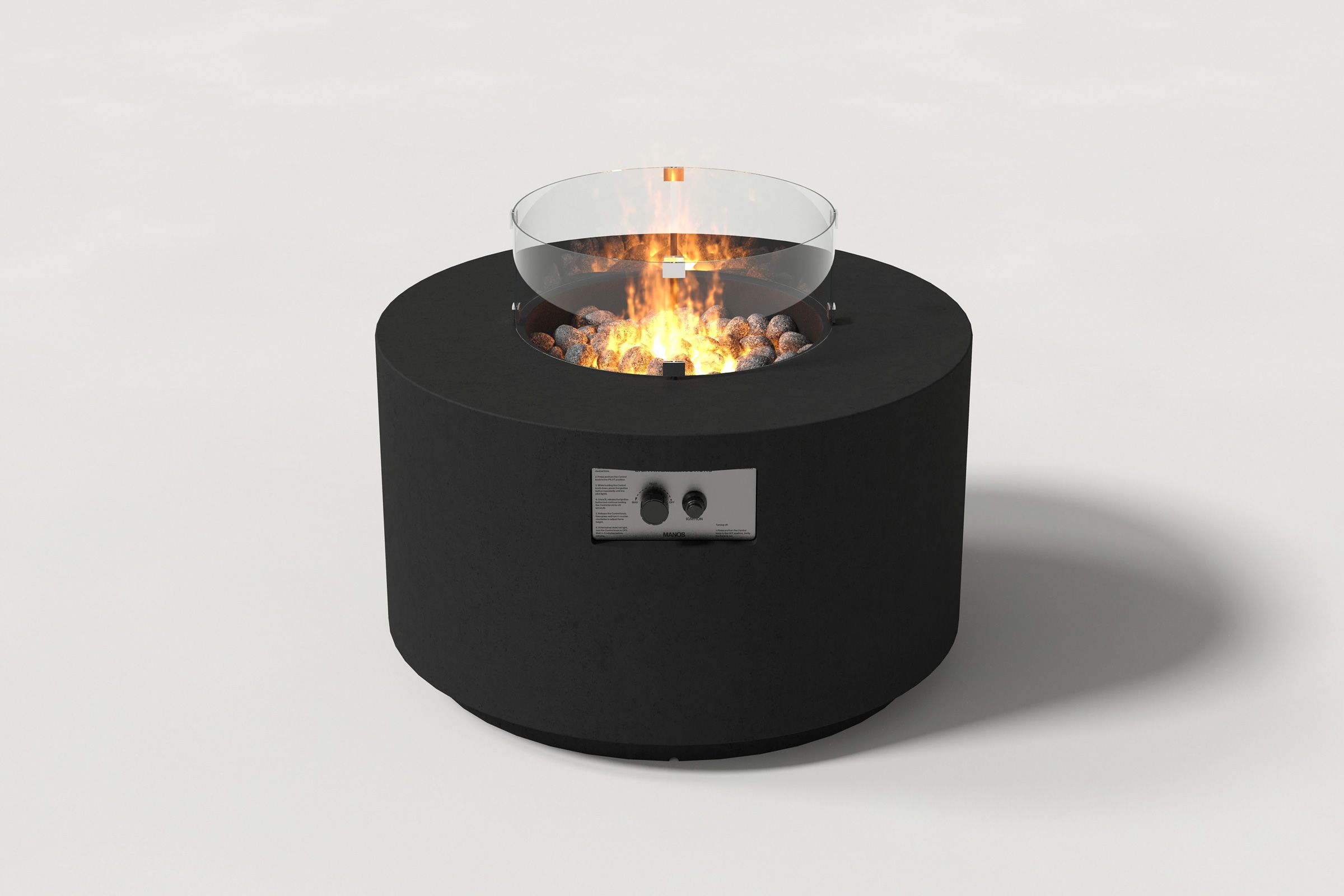 Low cylindrical black colored concrete fire pit with thick walls and a central circular well filled with dark volcanic rocks and flame, surrounded by a clear glass shield. Side view on a white background with a shadow to the right.