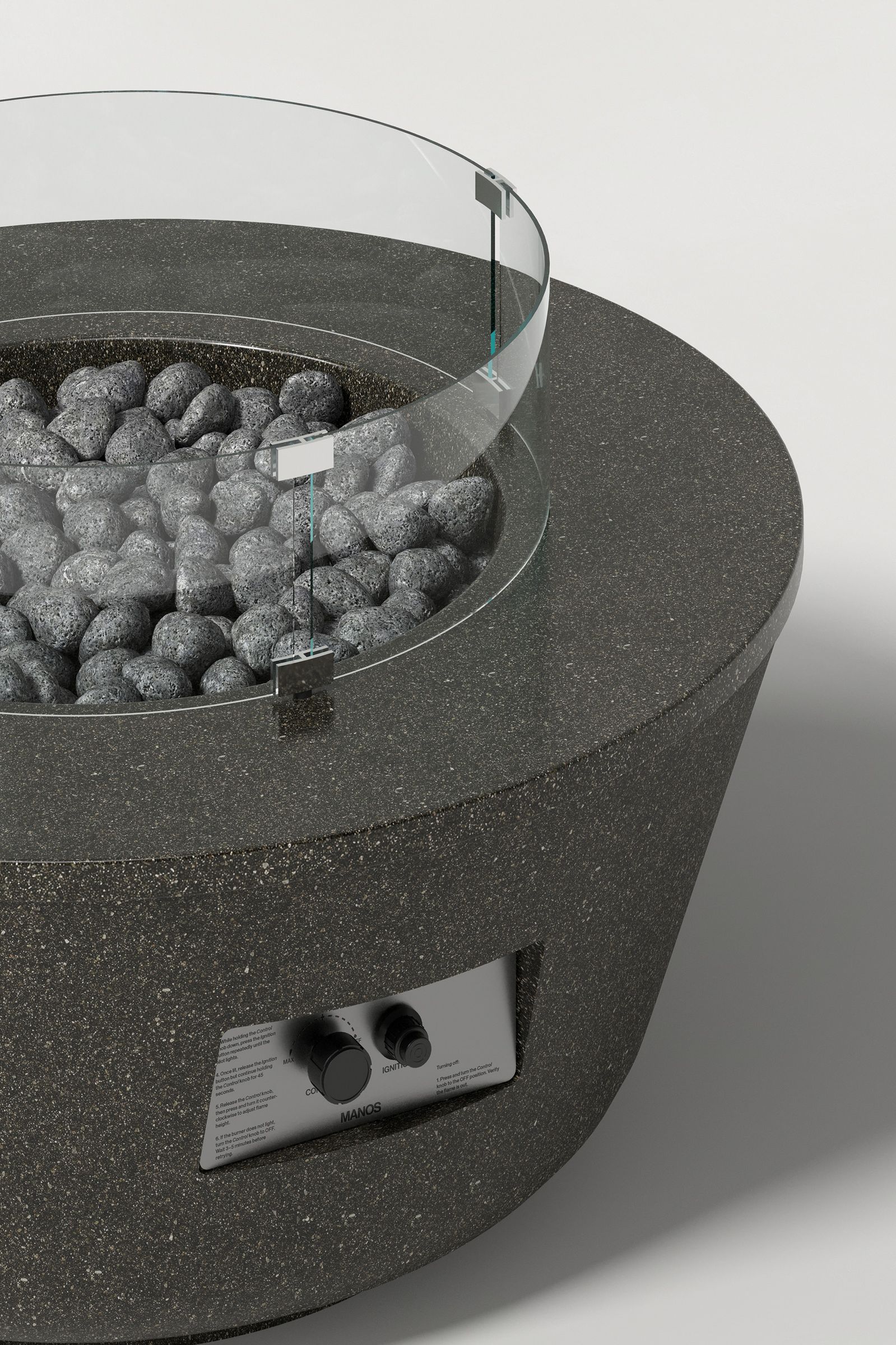 Close-up of a round dark grey concrete fire pit with a honed top and etched sides, showing the glass shield, lava rocks, and integrated control panel on the textured concrete surface.