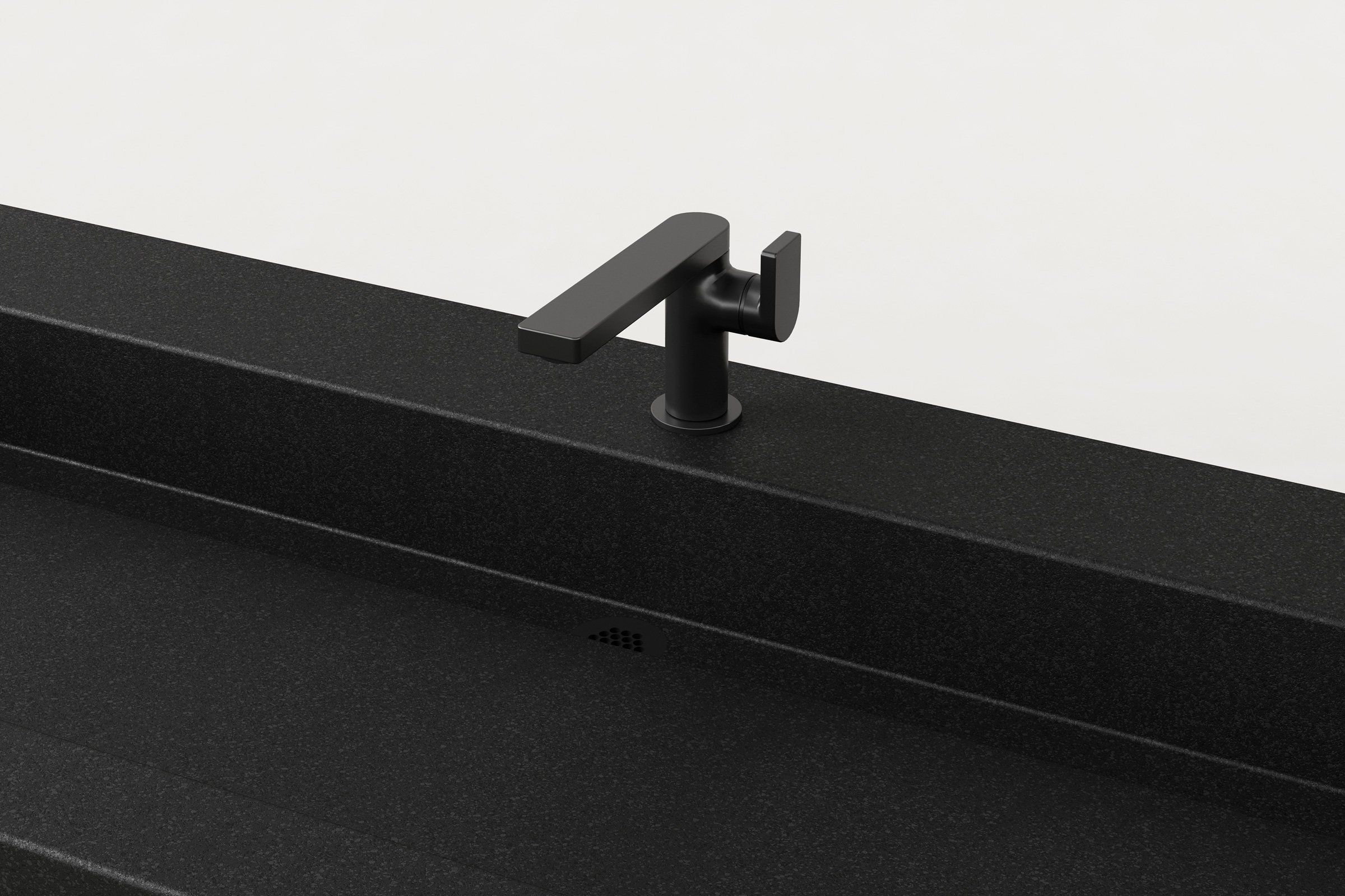 Close-up of matte black faucet on black concrete trough sink, showing drain detail.