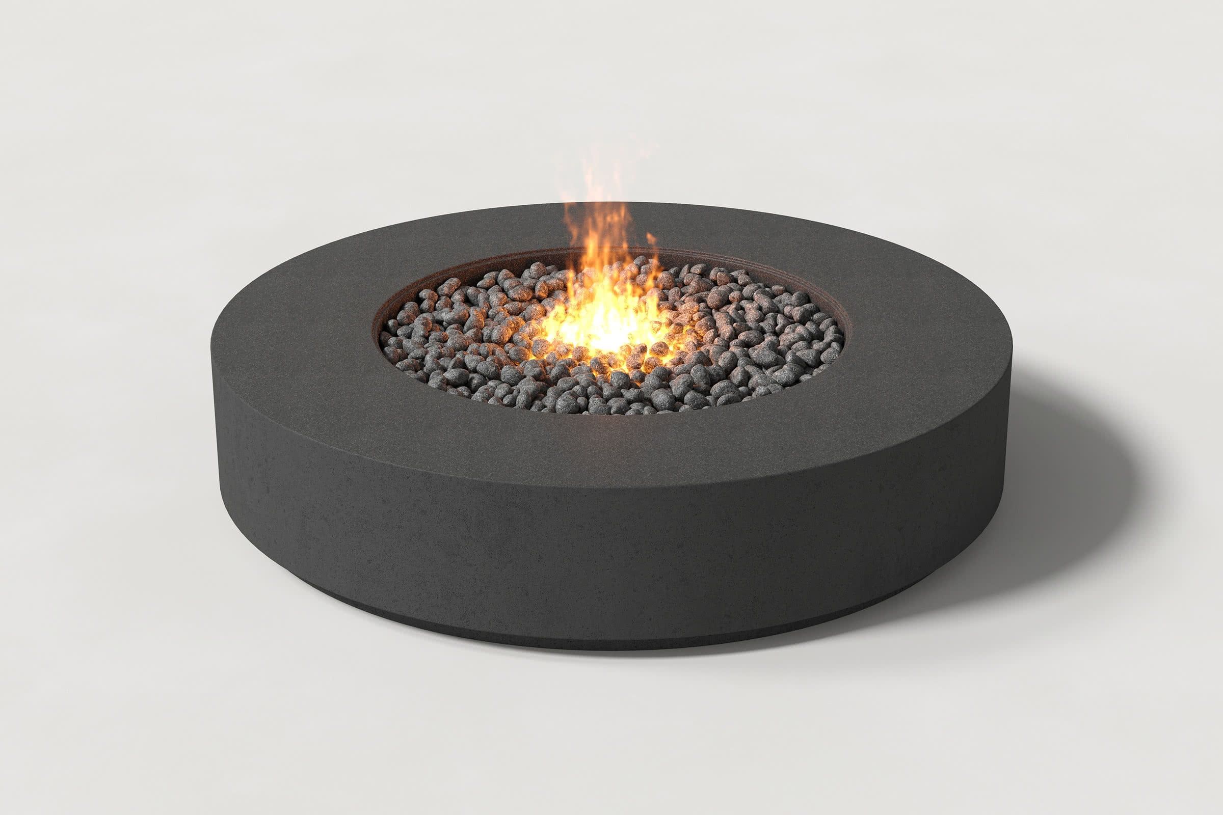 Low cylindrical charcoal concrete fire pit with thick walls and central circular well. Mid-range angle shows well filled with flaming volcanic rocks on a white background.
