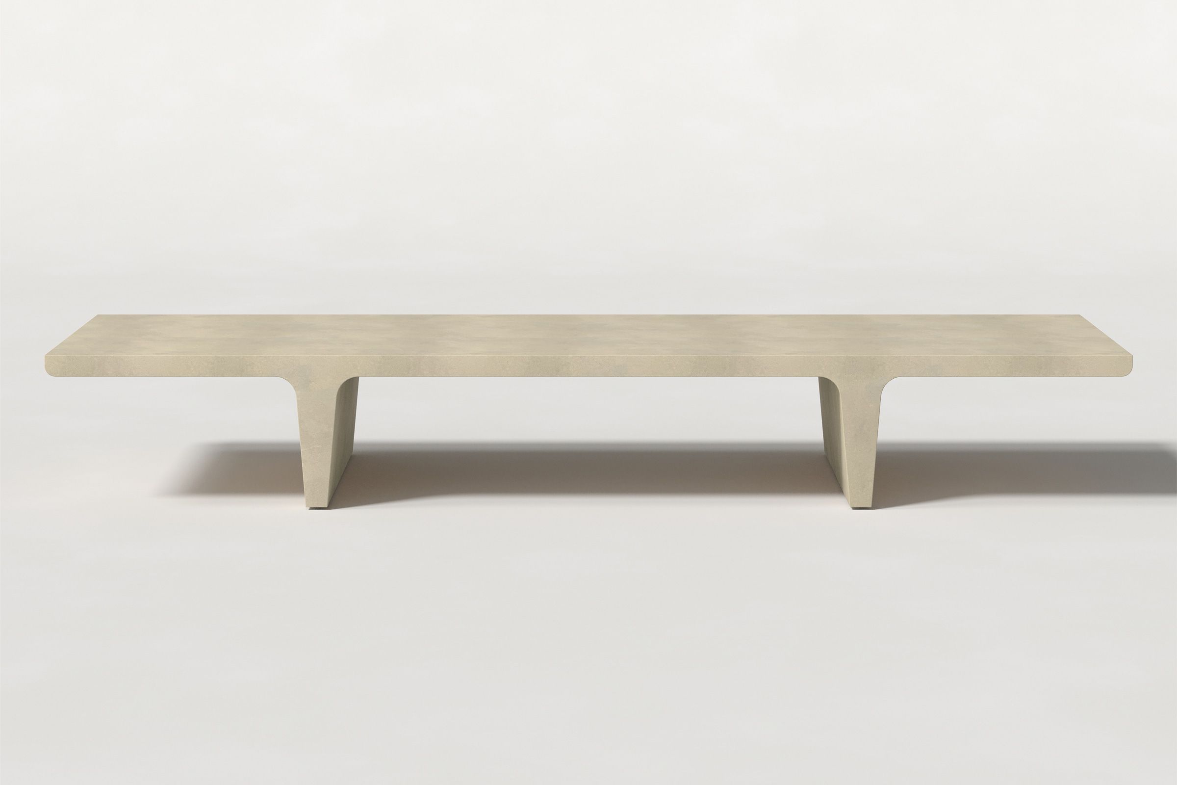 Long rectangular solid light beige concrete coffee table with sculptural double tee legs and a smooth top, set against a clean white background.
