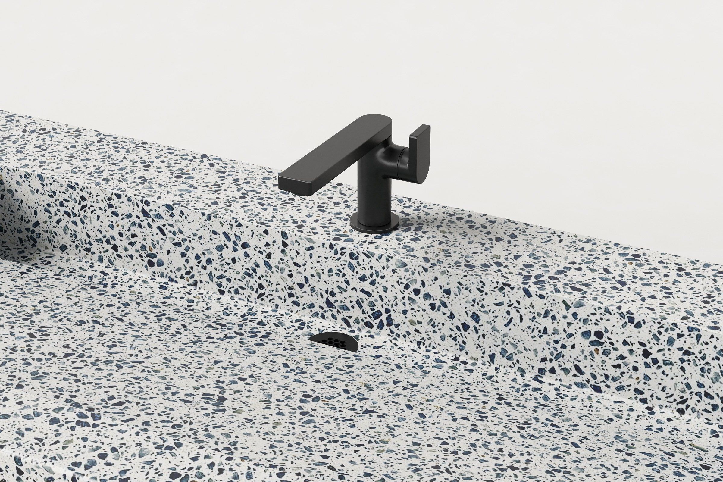 Close-up view of faucet and drain detail on the speckled terrazzo surface.