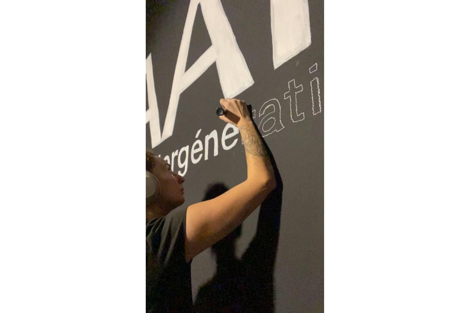 Gwenn écrit le titre de l’exposition au mur