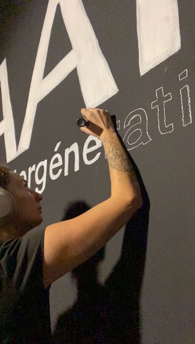 Gwenn écrit le titre de l’exposition au mur