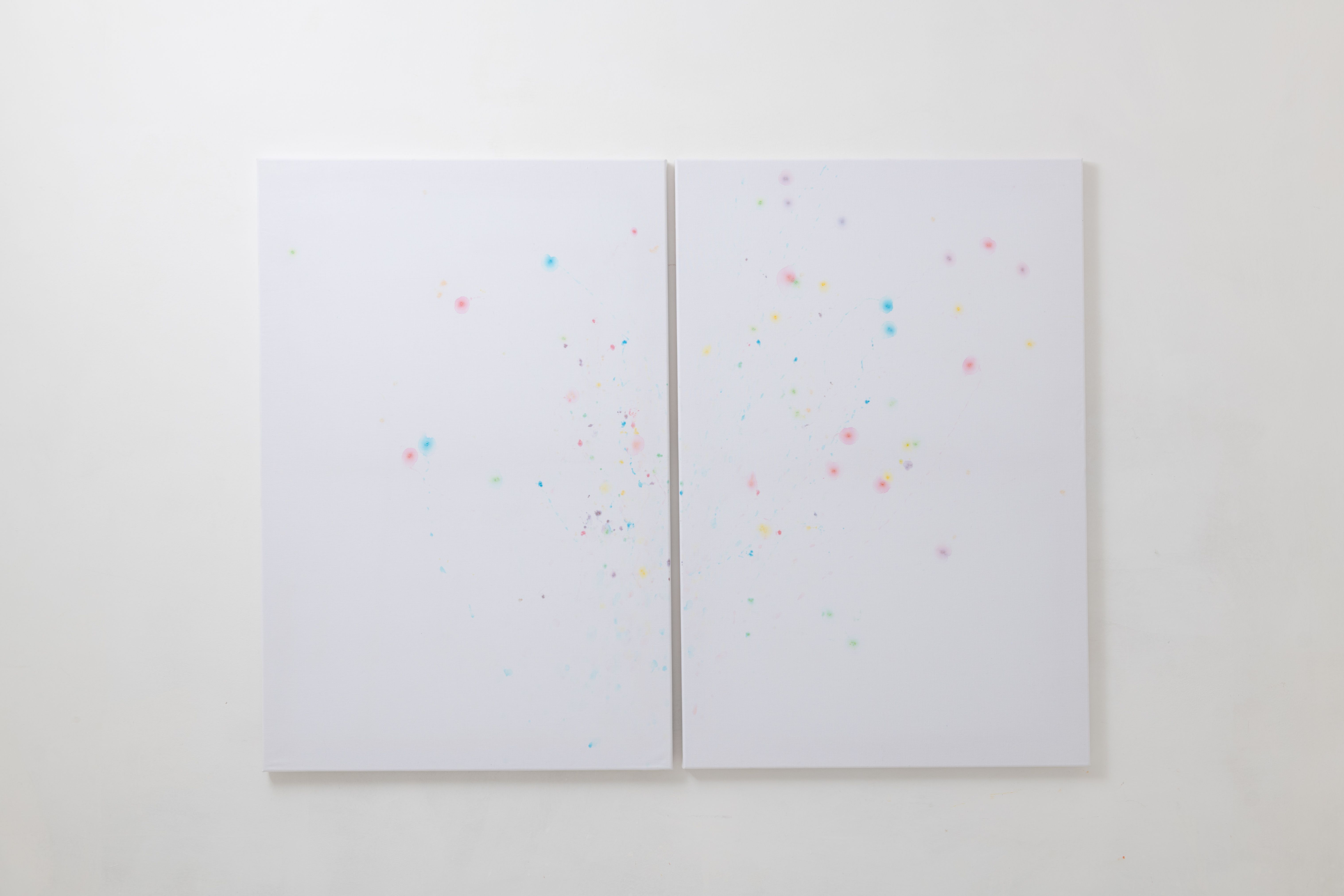 Diptych of white sheets with pink and blue stains on a white wall