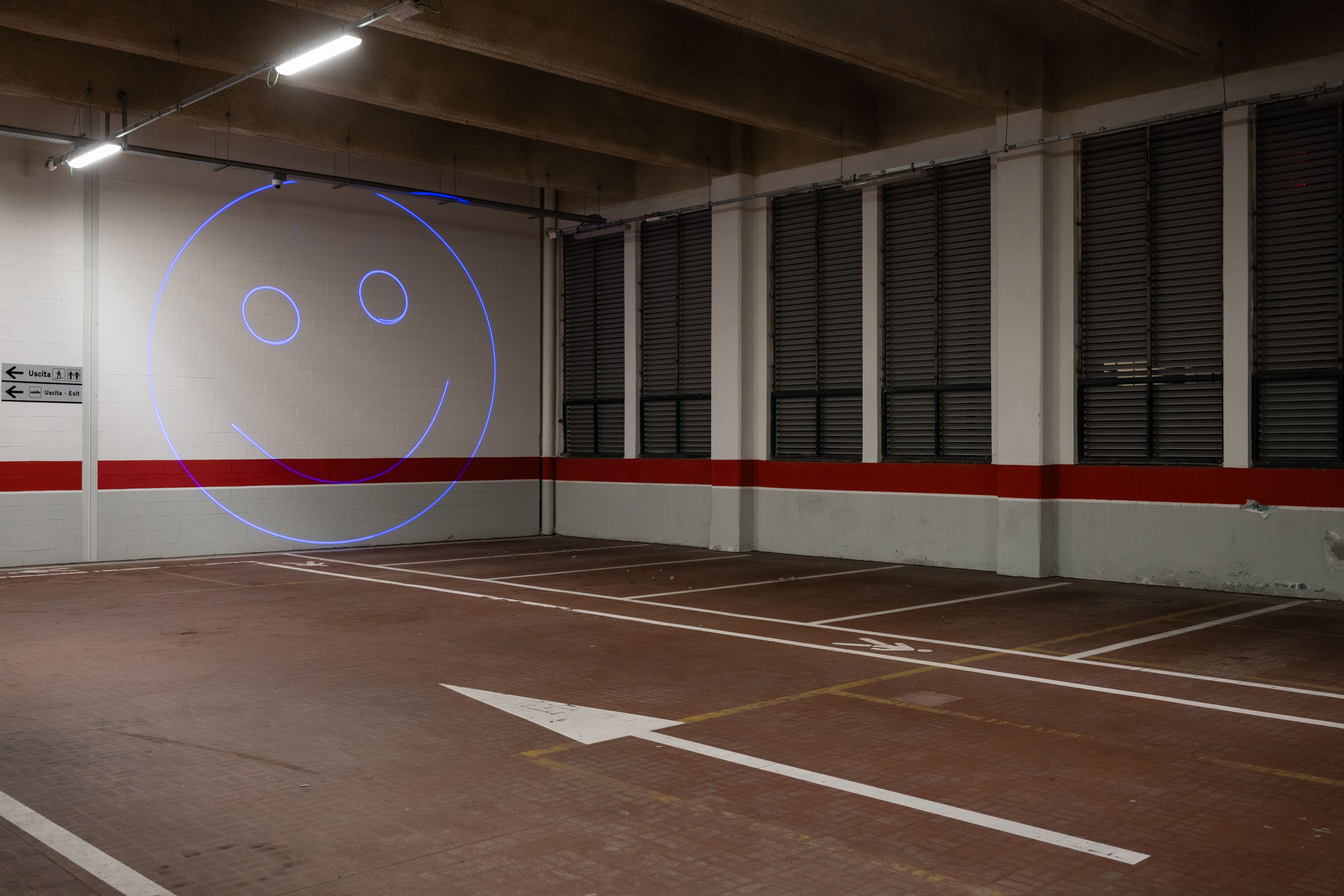 Blue laser smiley face projected on the wall of an underground car park