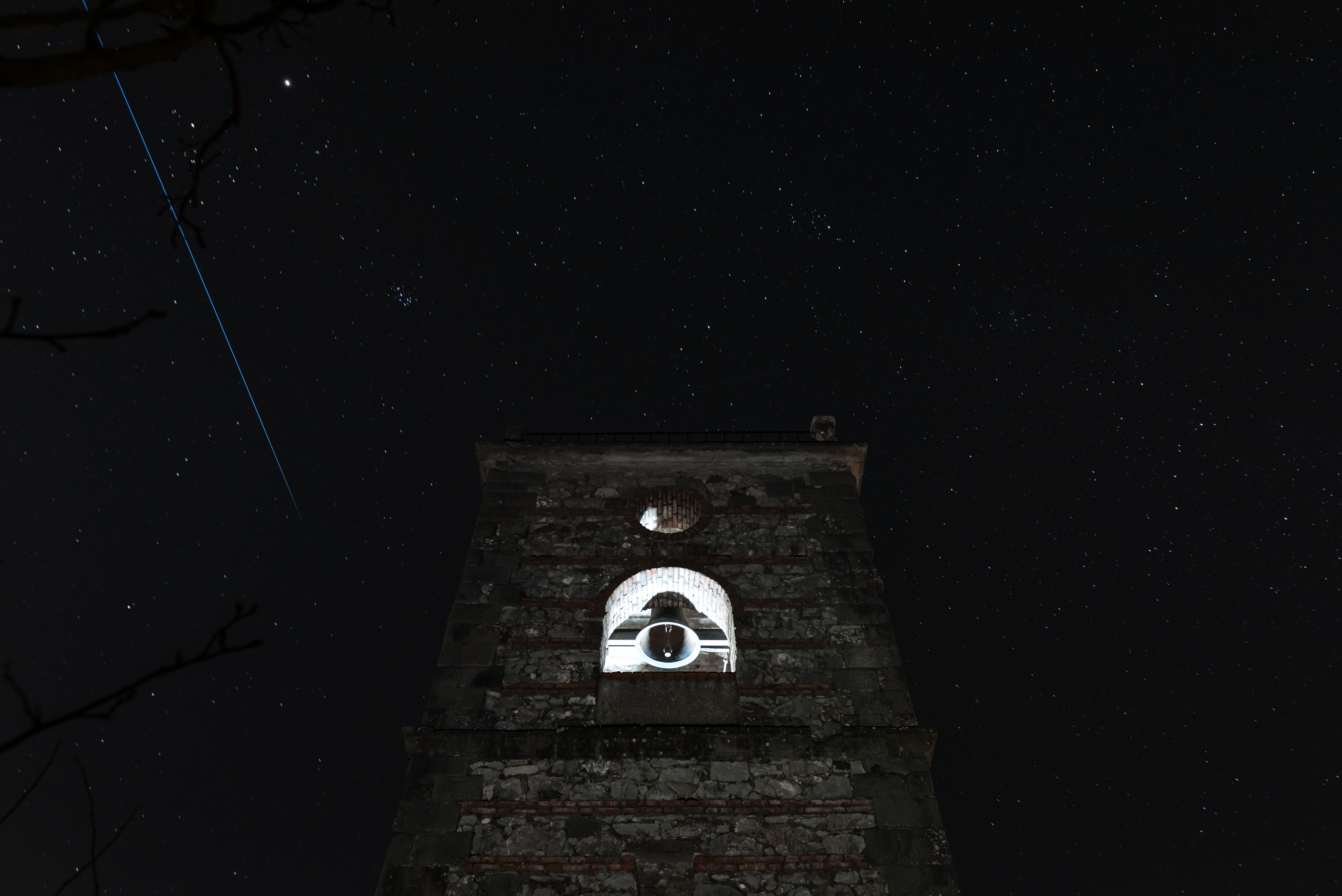Bell tower against a starry night sky with its belfry glowing white