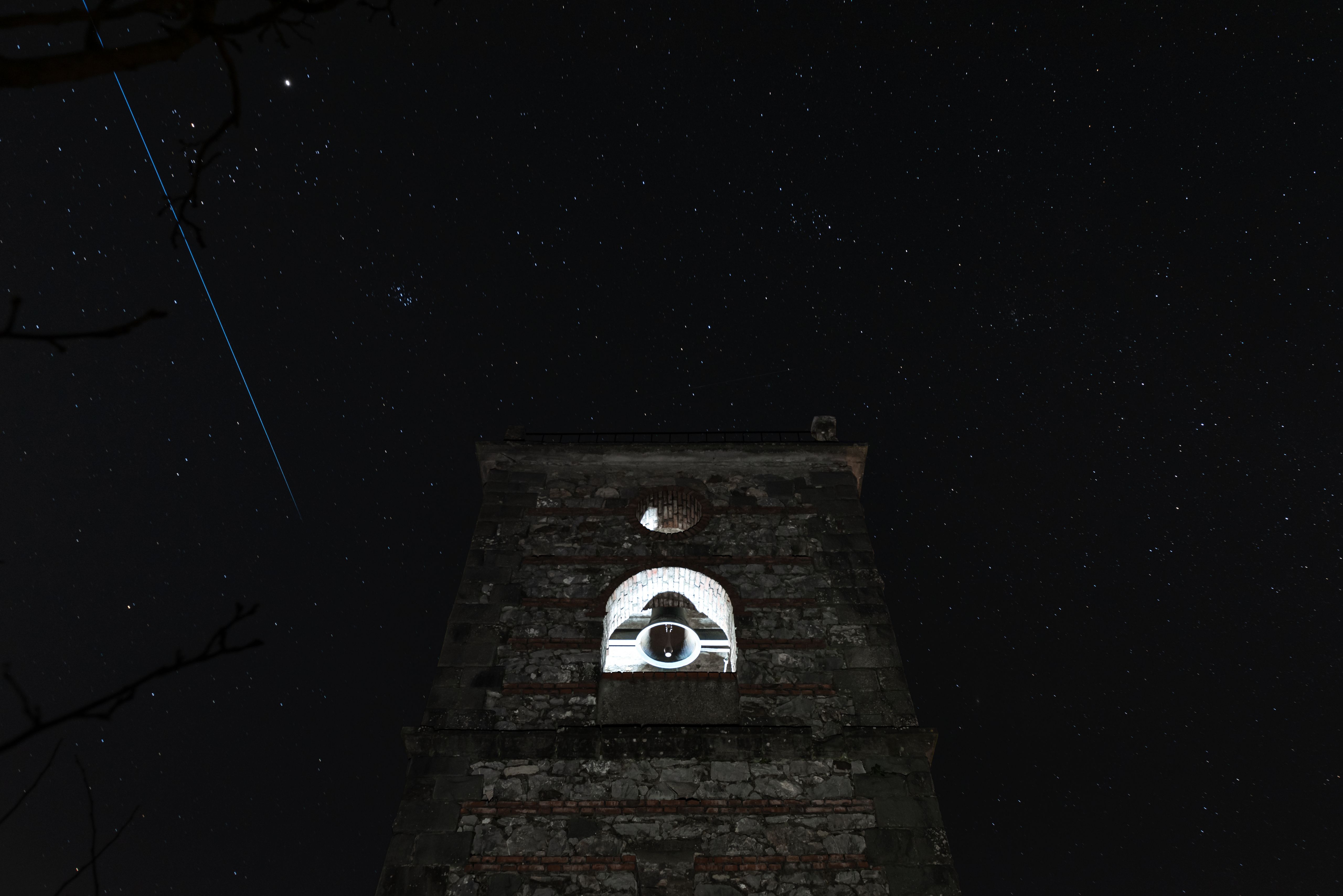 Bell tower against a starry night sky with its belfry glowing white
