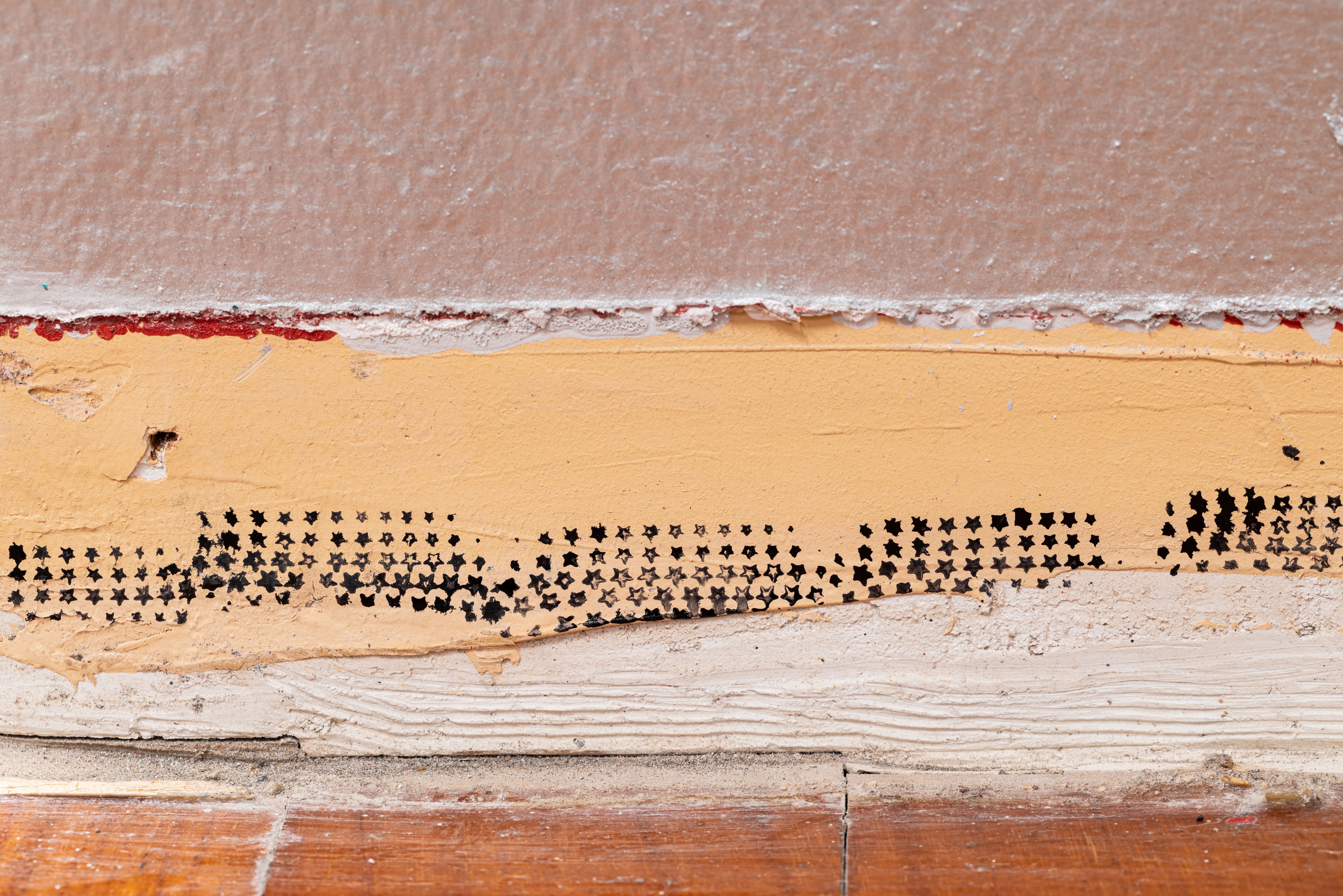 Detail of black star patterns printed on a worn skirting board