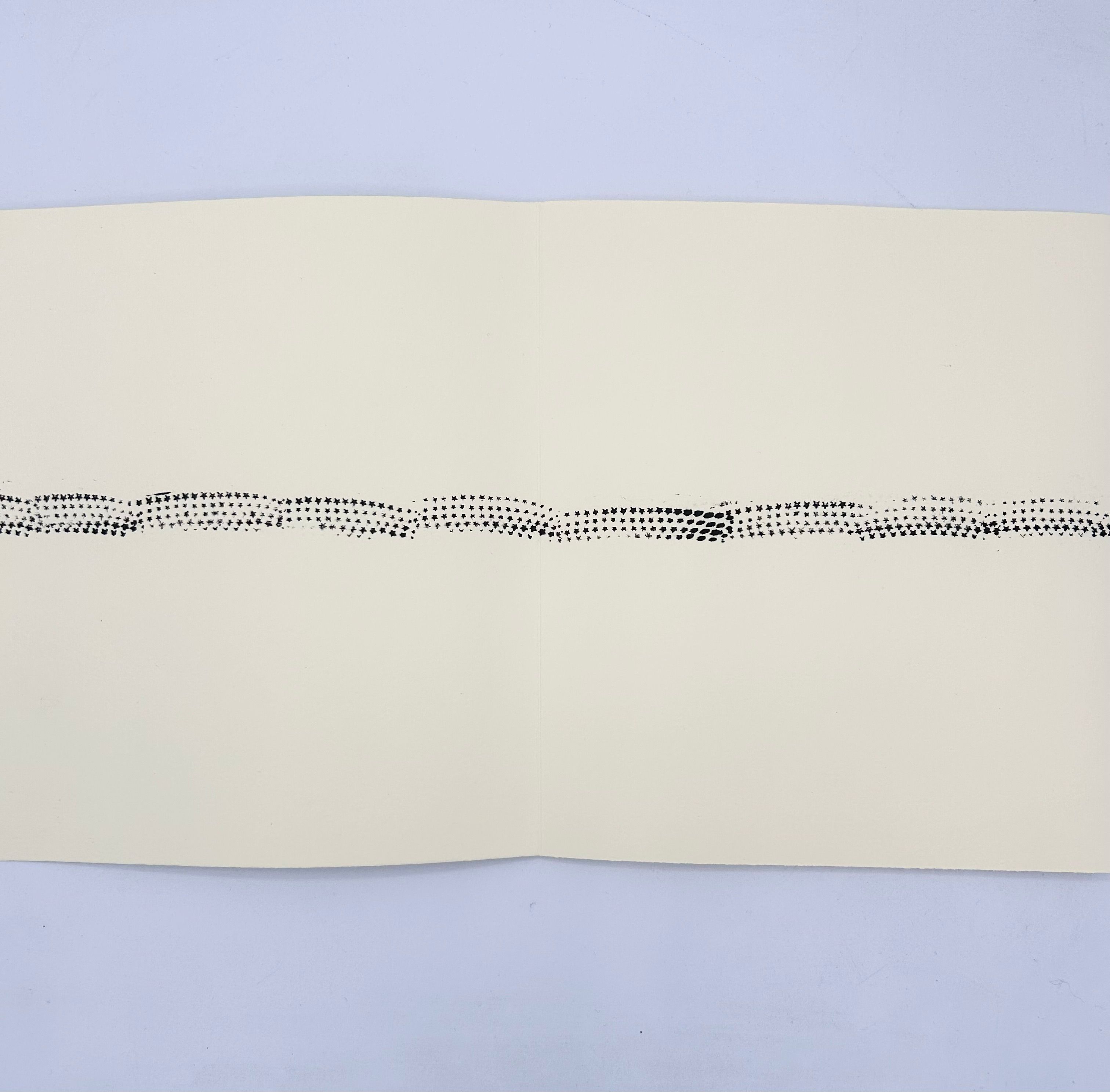 Unfolded leporello book with a line of black star prints across cream paper