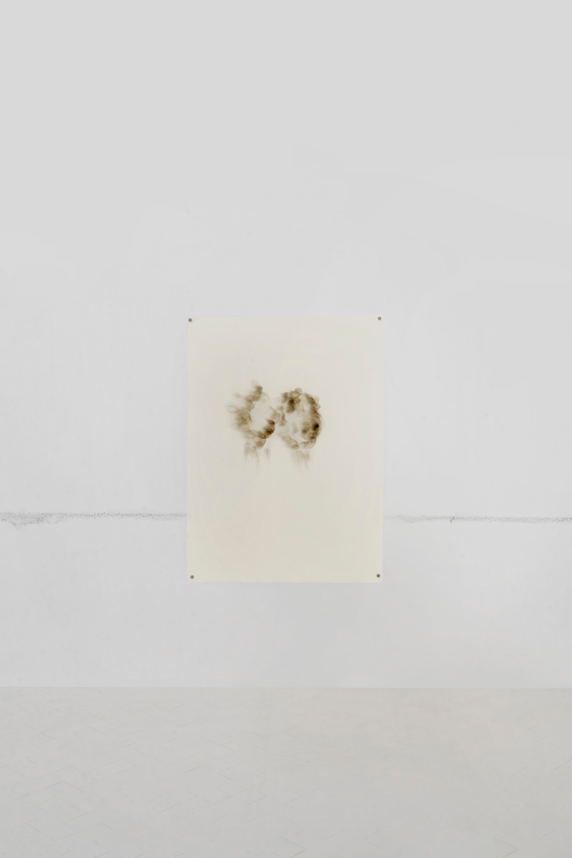 Lemon juice drawing of a pair of eyes hung on a white gallery wall
