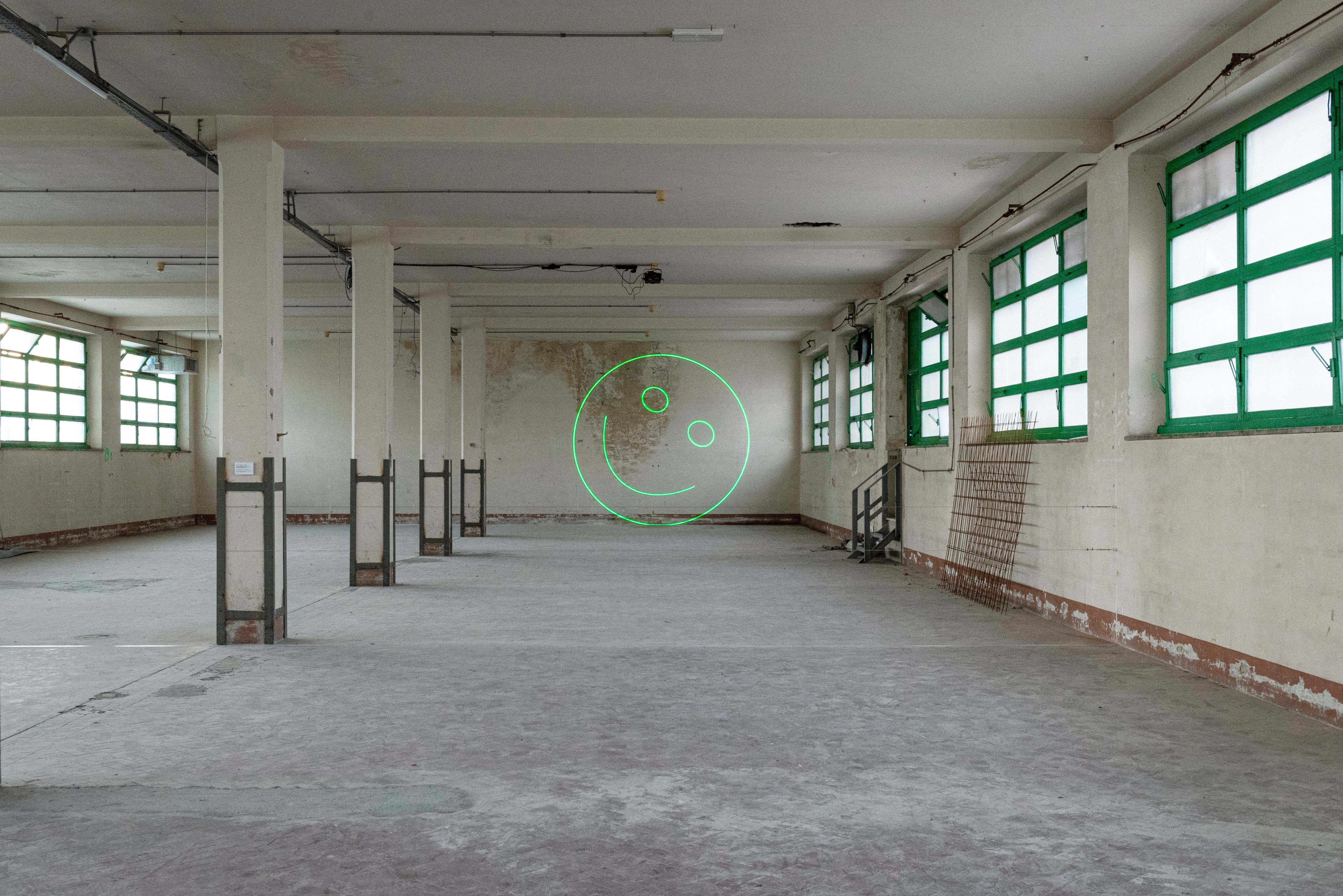 Green laser smiley glowing at the end of a long empty industrial hall