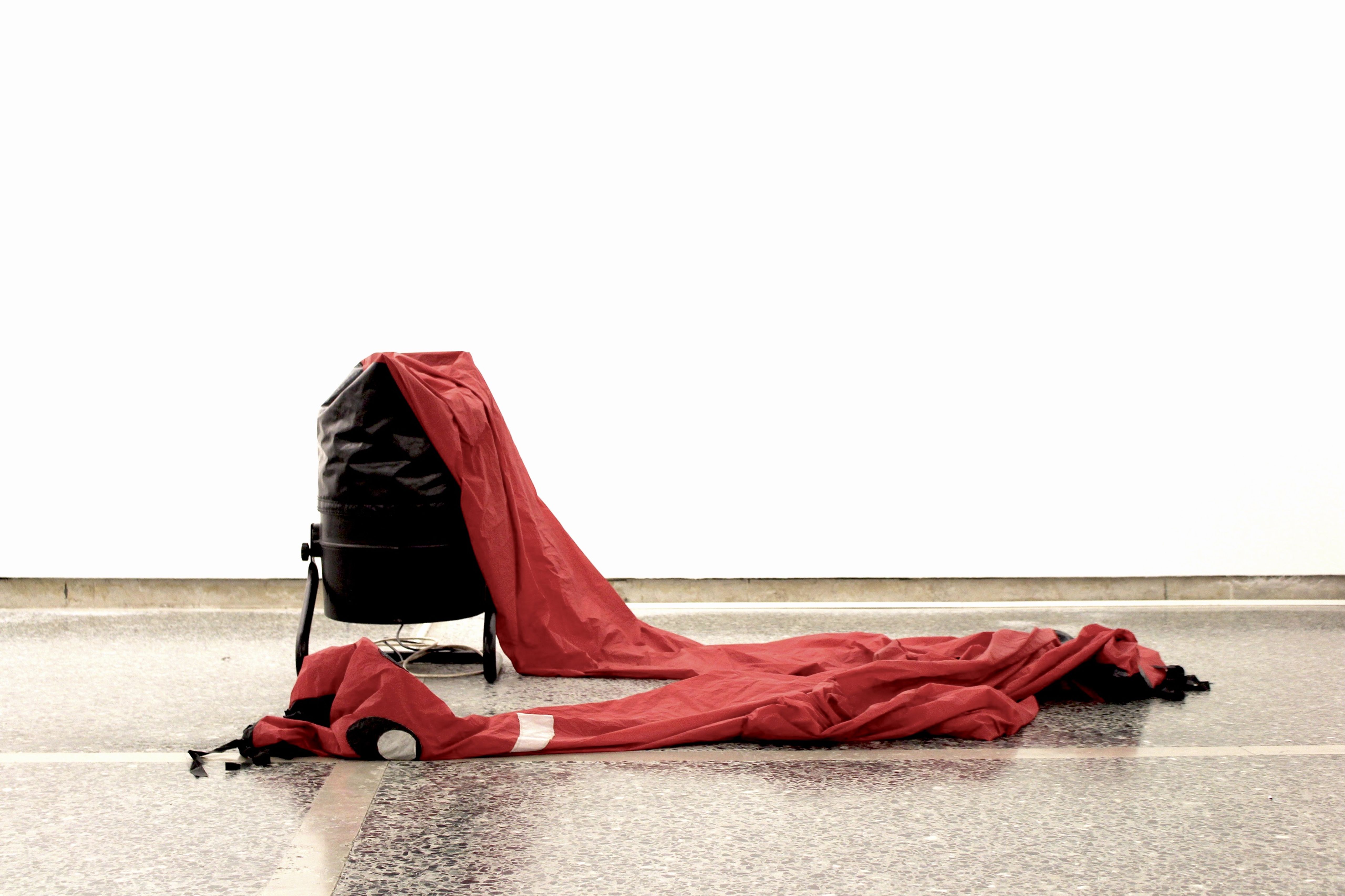 Deflated red skydancer lying on the floor next to its fan