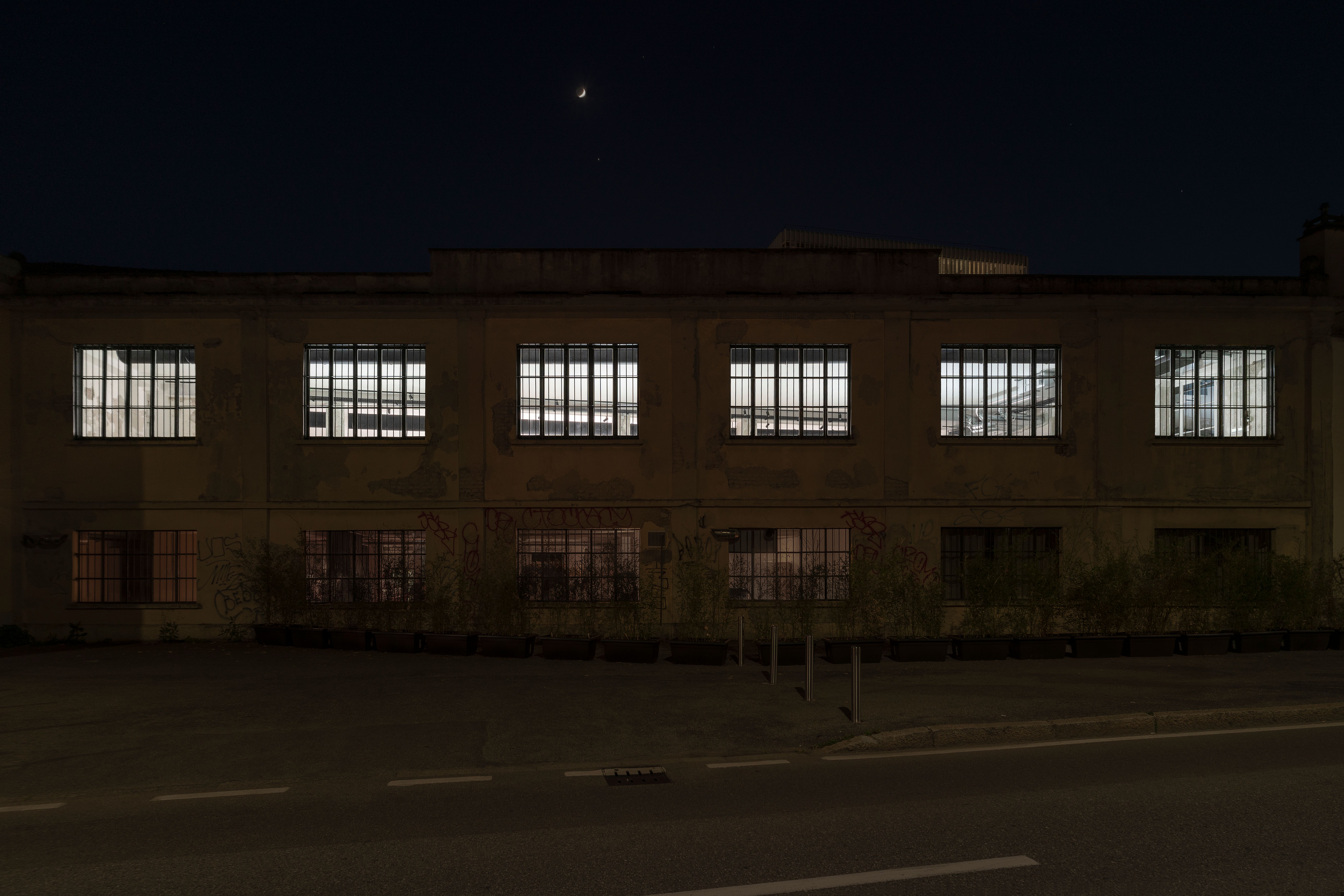 Industrial building facade at night with its row of windows lit white by strobe lights