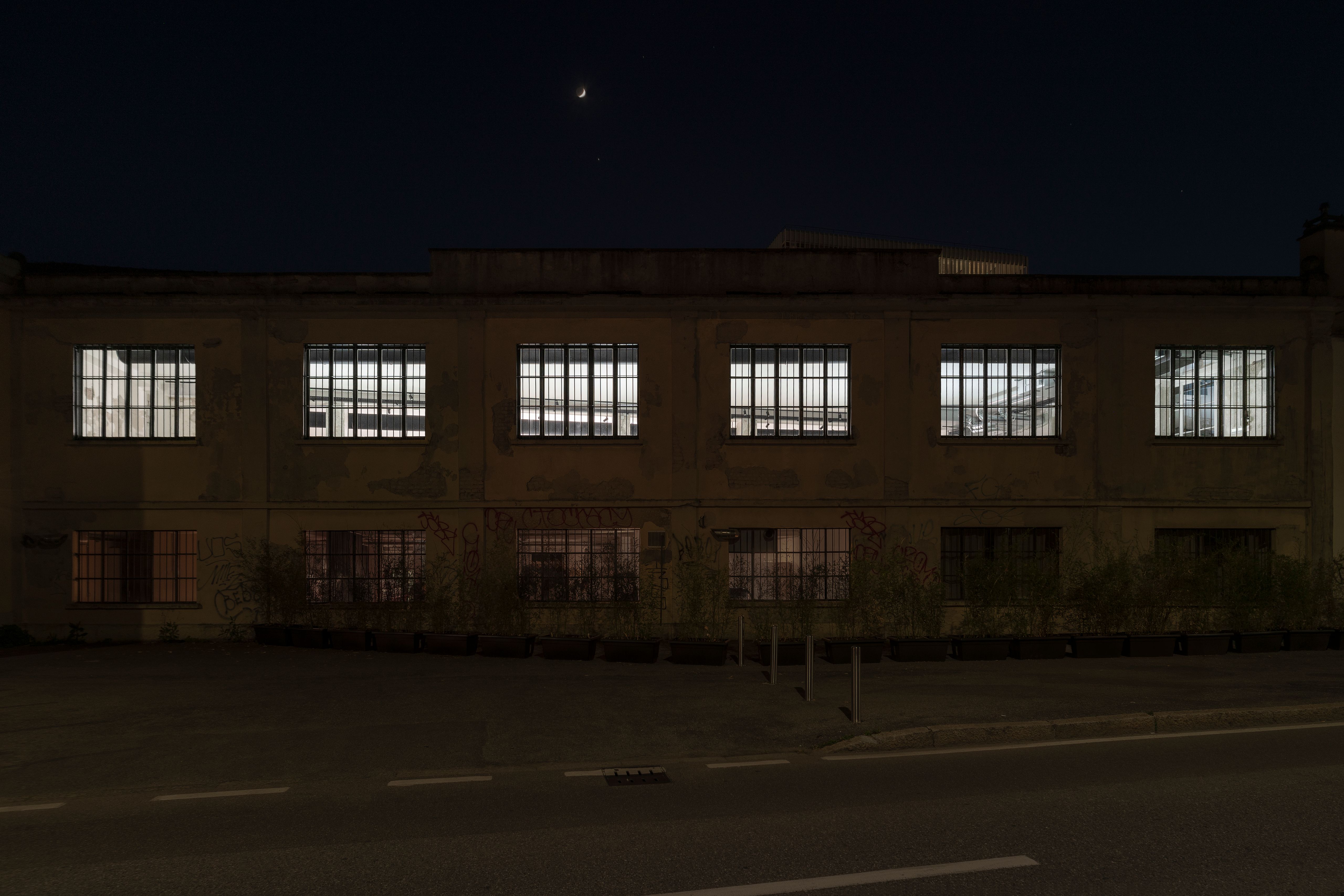 Industrial building facade at night with its row of windows lit white by strobe lights