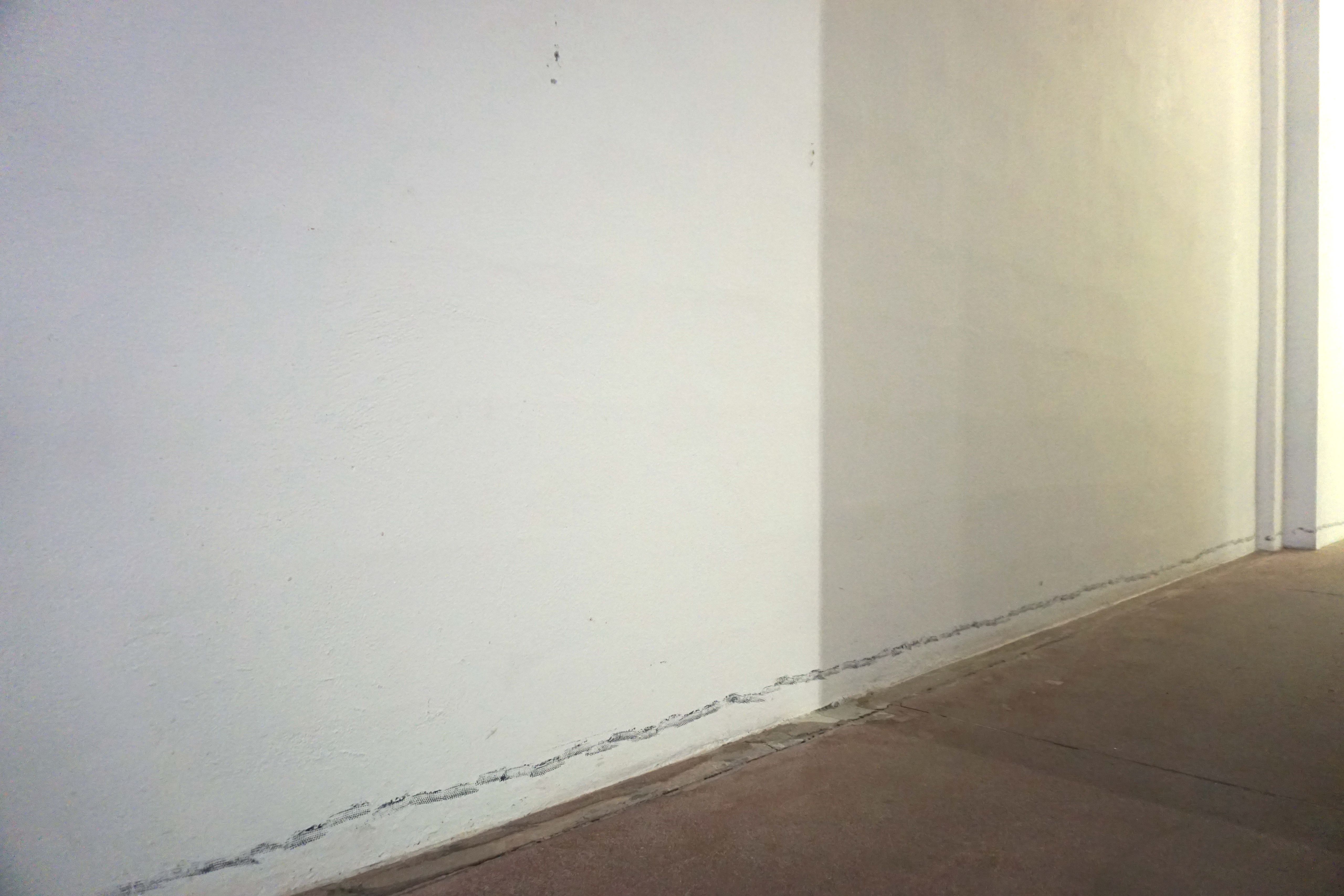 White walls with a line of dark prints along the floor