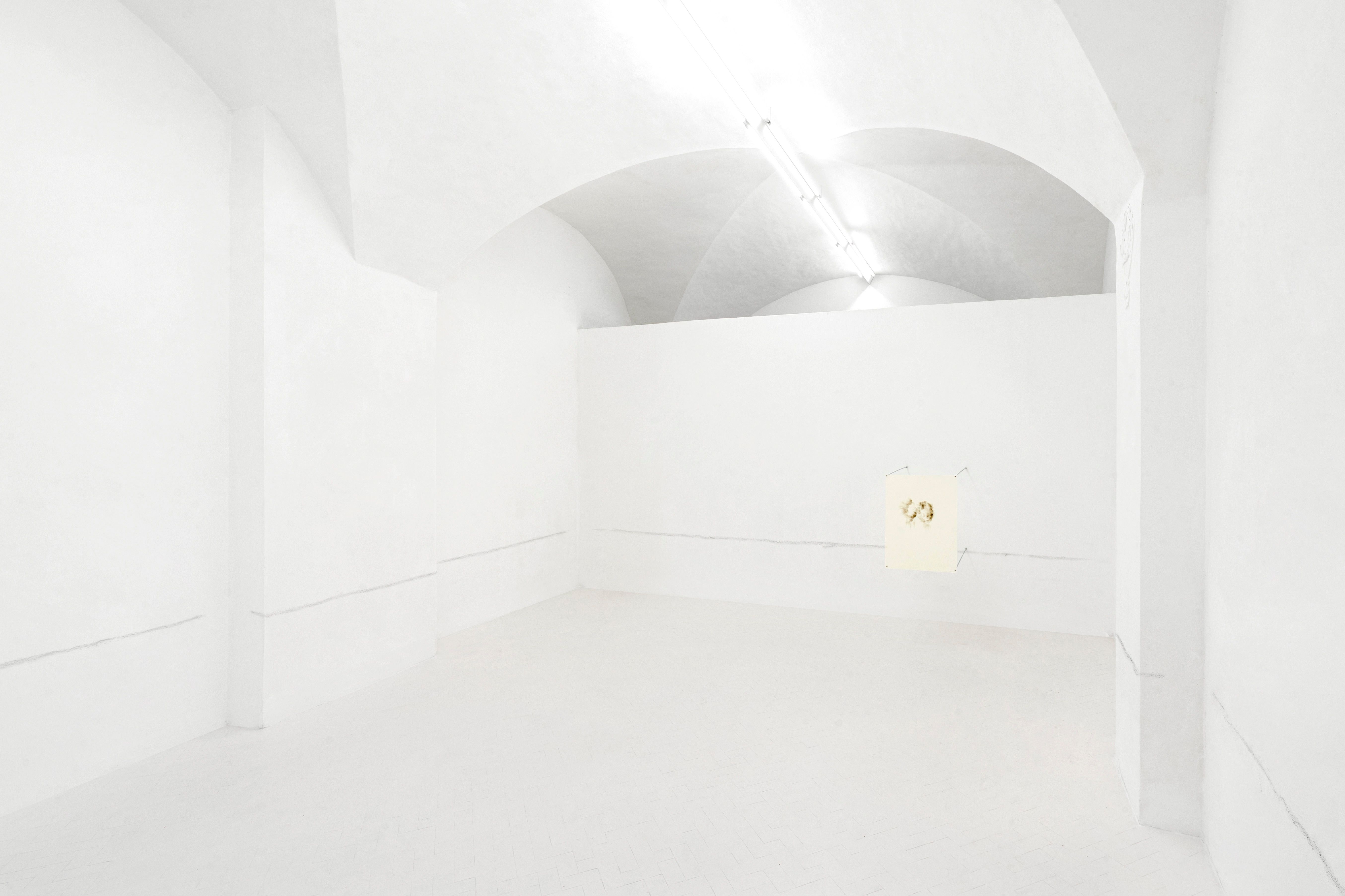 White vaulted gallery with a line of scuff marks along the walls and a small drawing on the far wall