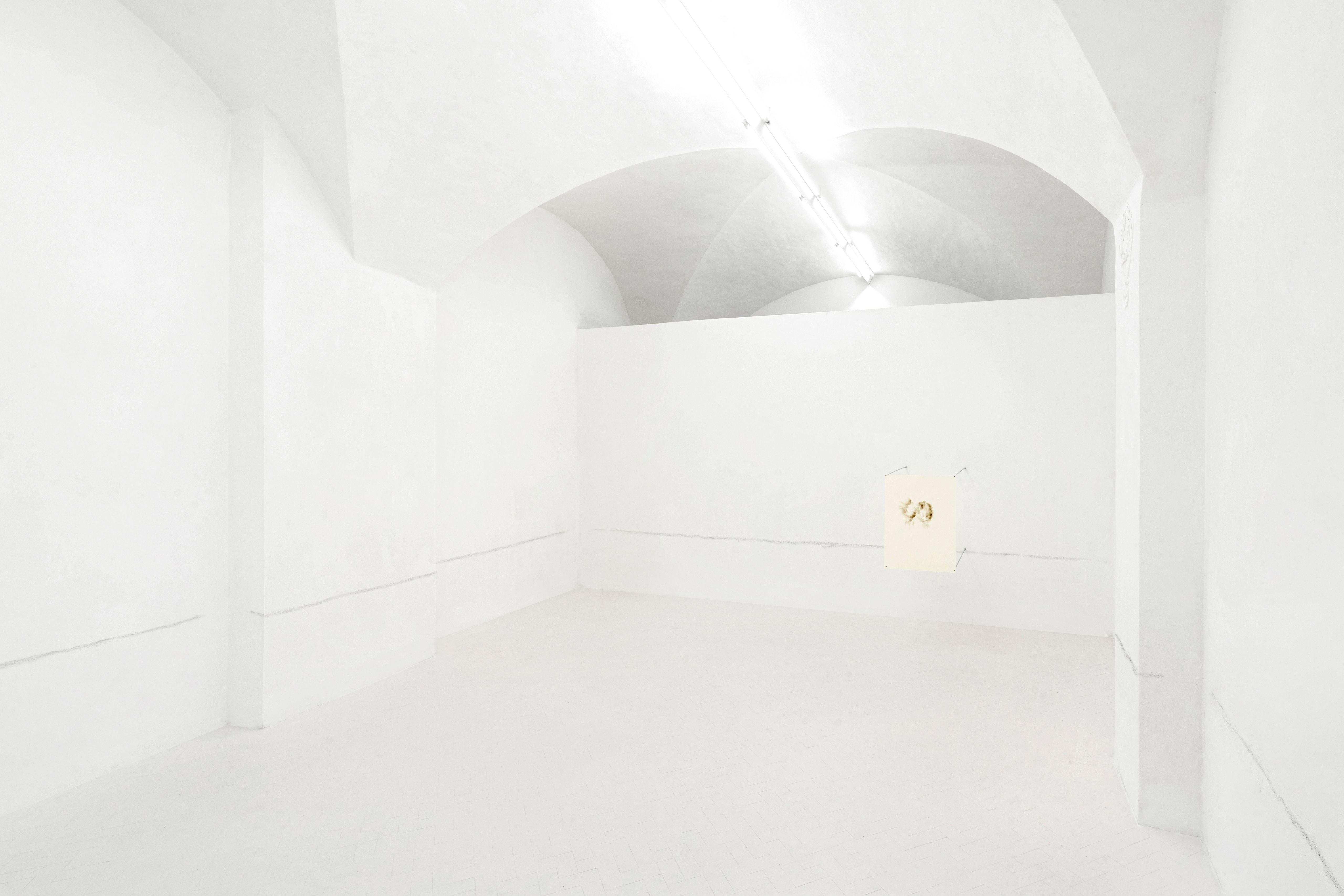 White vaulted gallery with a line of scuff marks along the walls and a small drawing on the far wall
