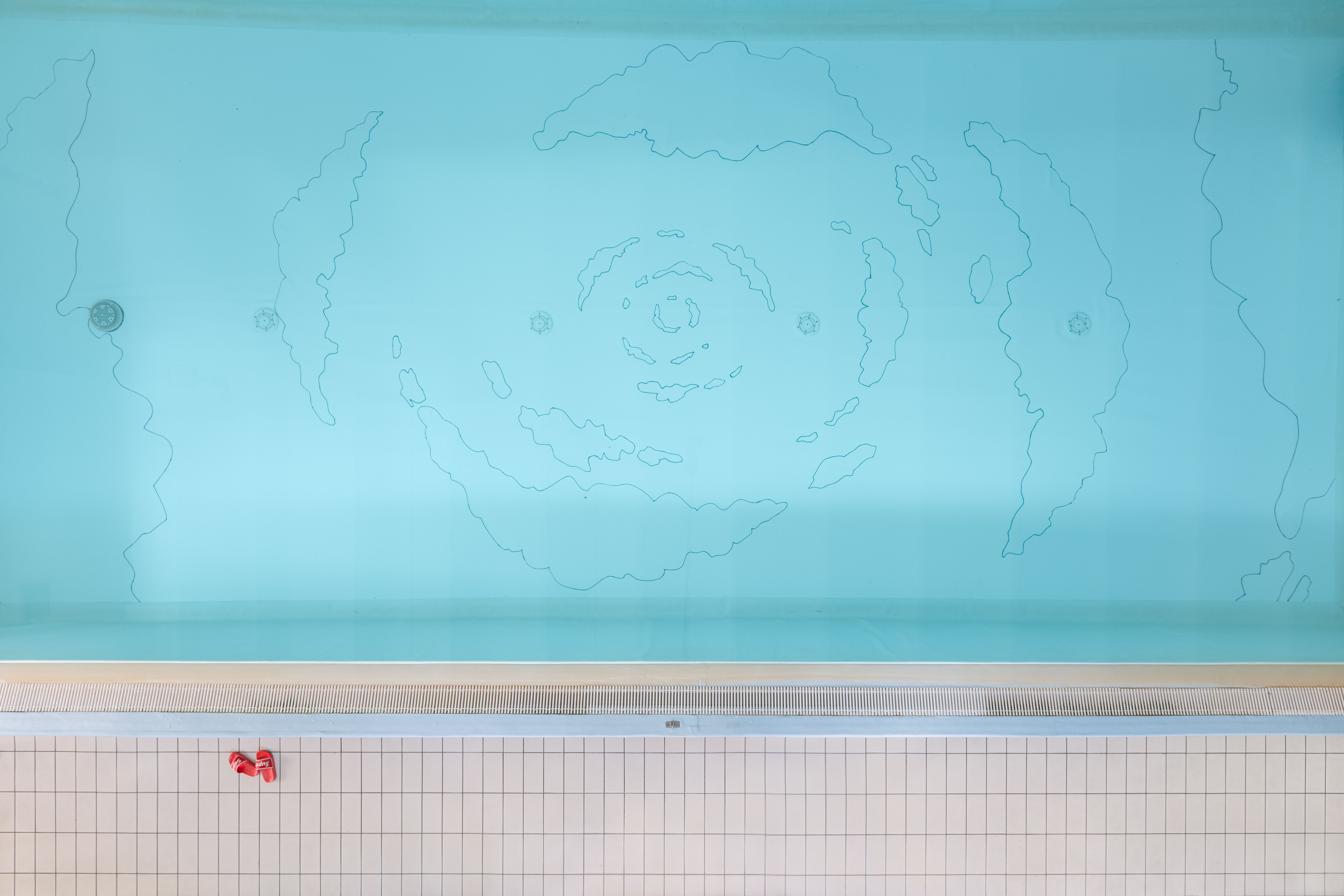 Turquoise pool seen from above, with a drawing of clouds swirling towards the centre on its floor