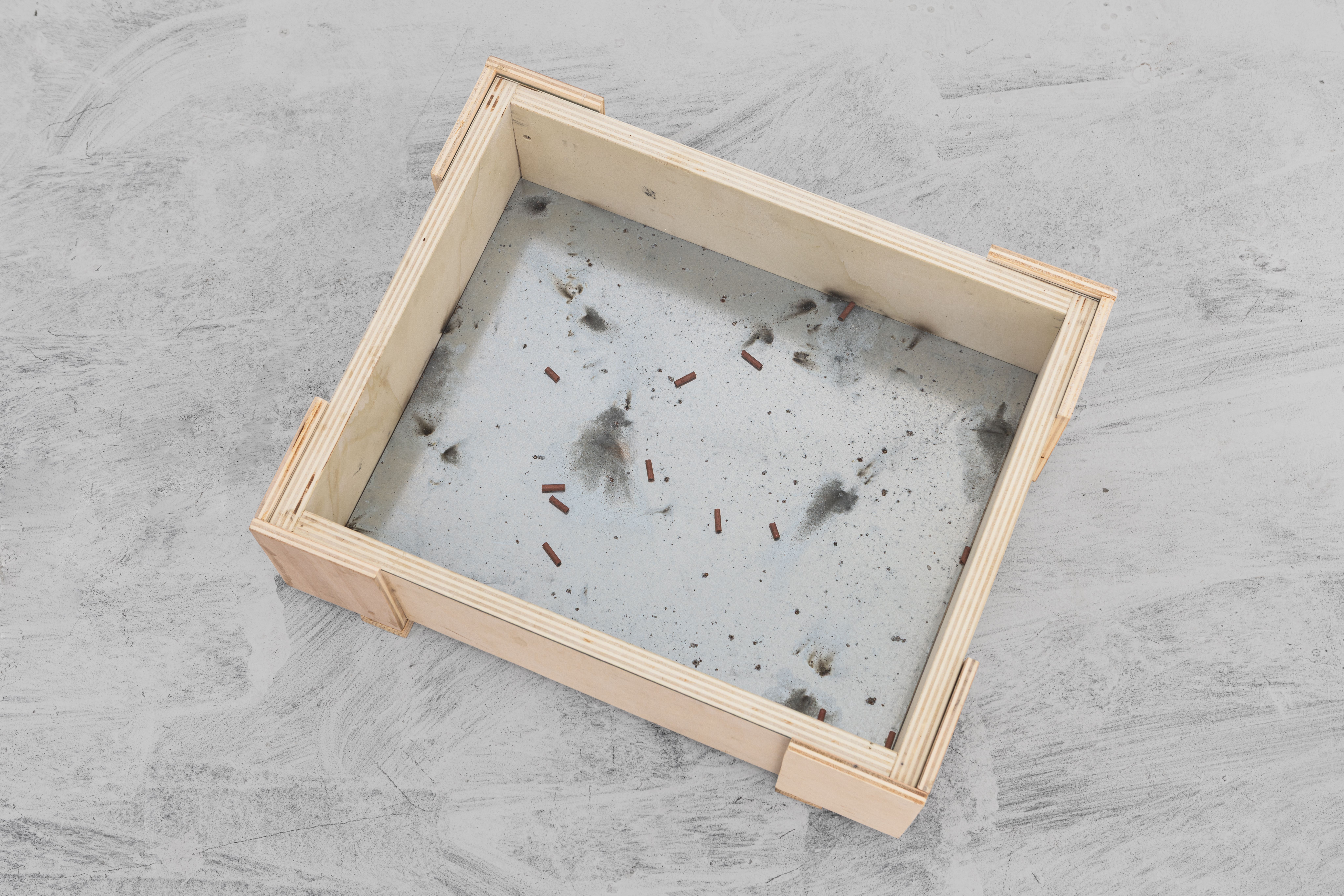 Wooden case seen from above with firecracker debris and soot on its glass bottom