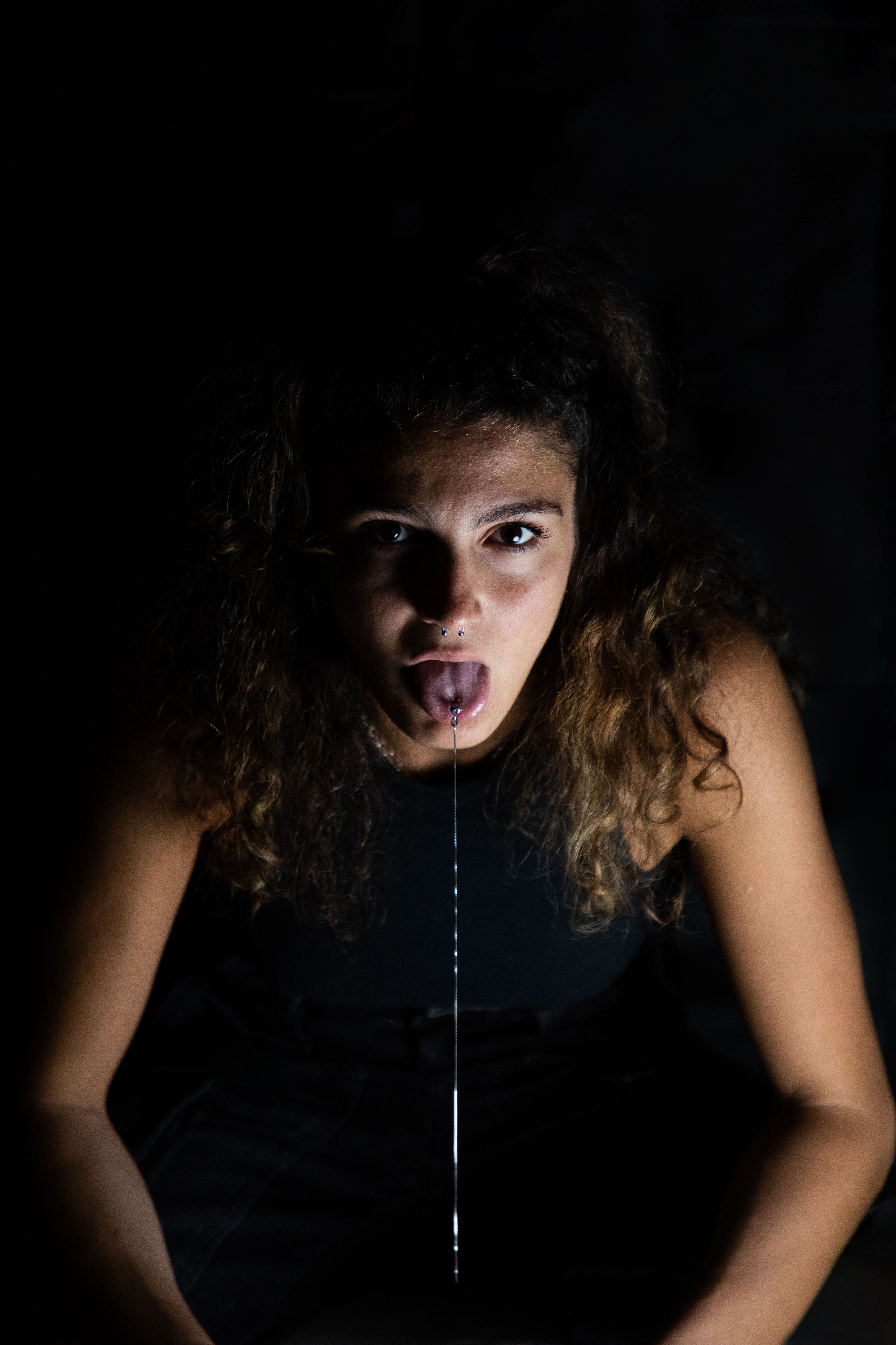 Woman sticking out her tongue with a long silver chain hanging from it