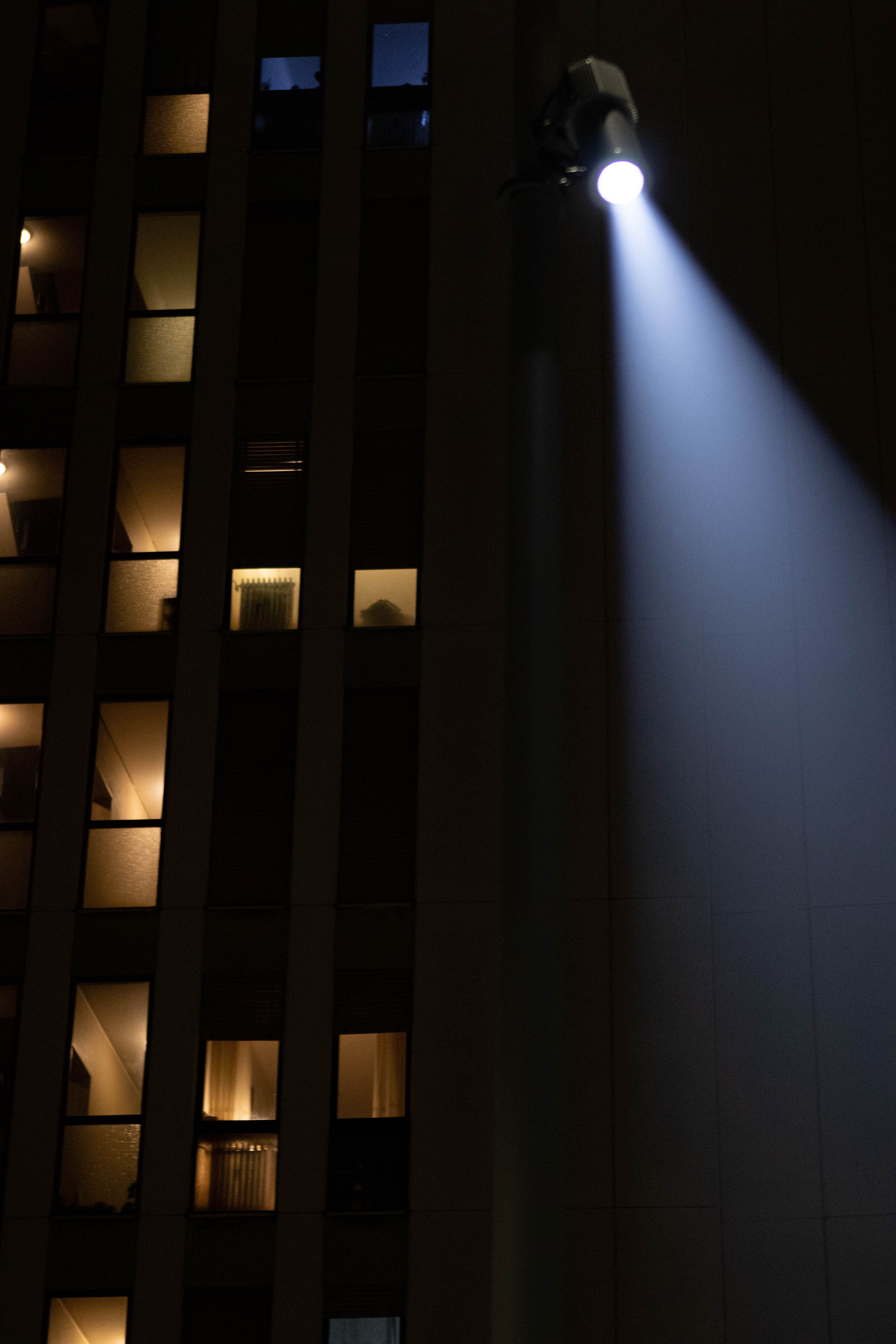 Light shaper on a pole beaming down beside a tall building with lit windows