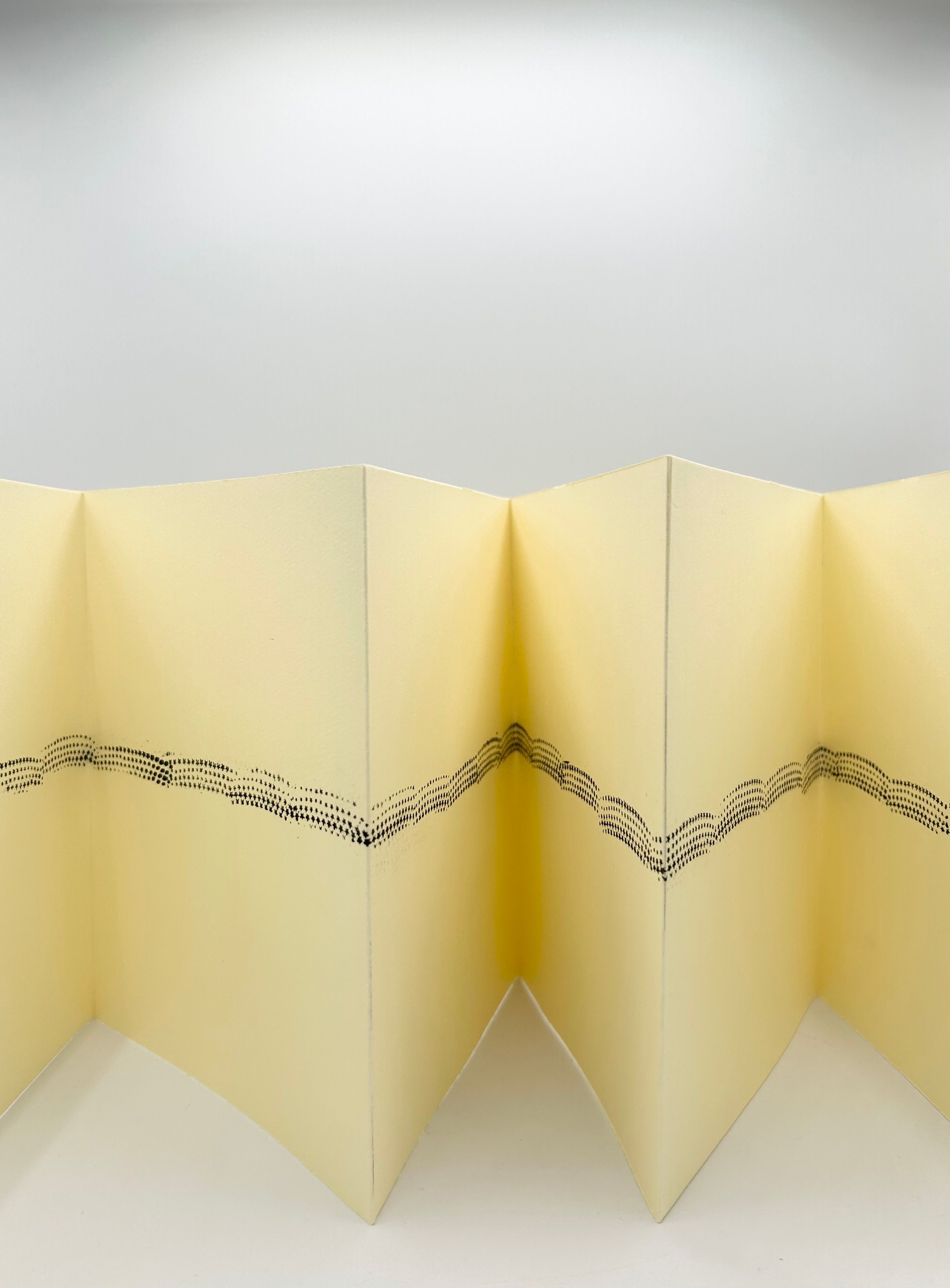Accordion-folded artist's book standing upright with a band of star prints