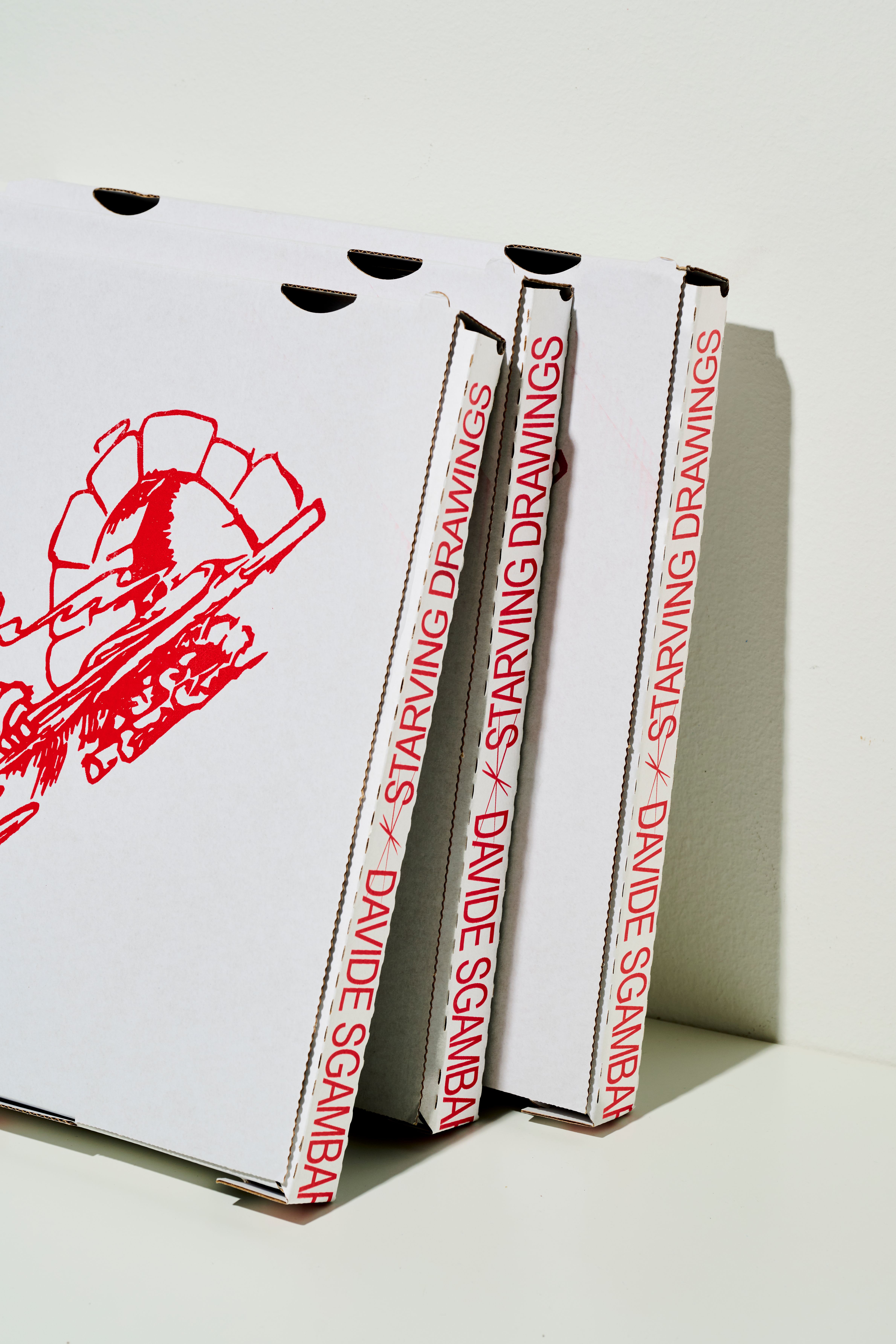 Three pizza box editions lined up, spines reading STARVING DRAWINGS DAVIDE SGAMBARO