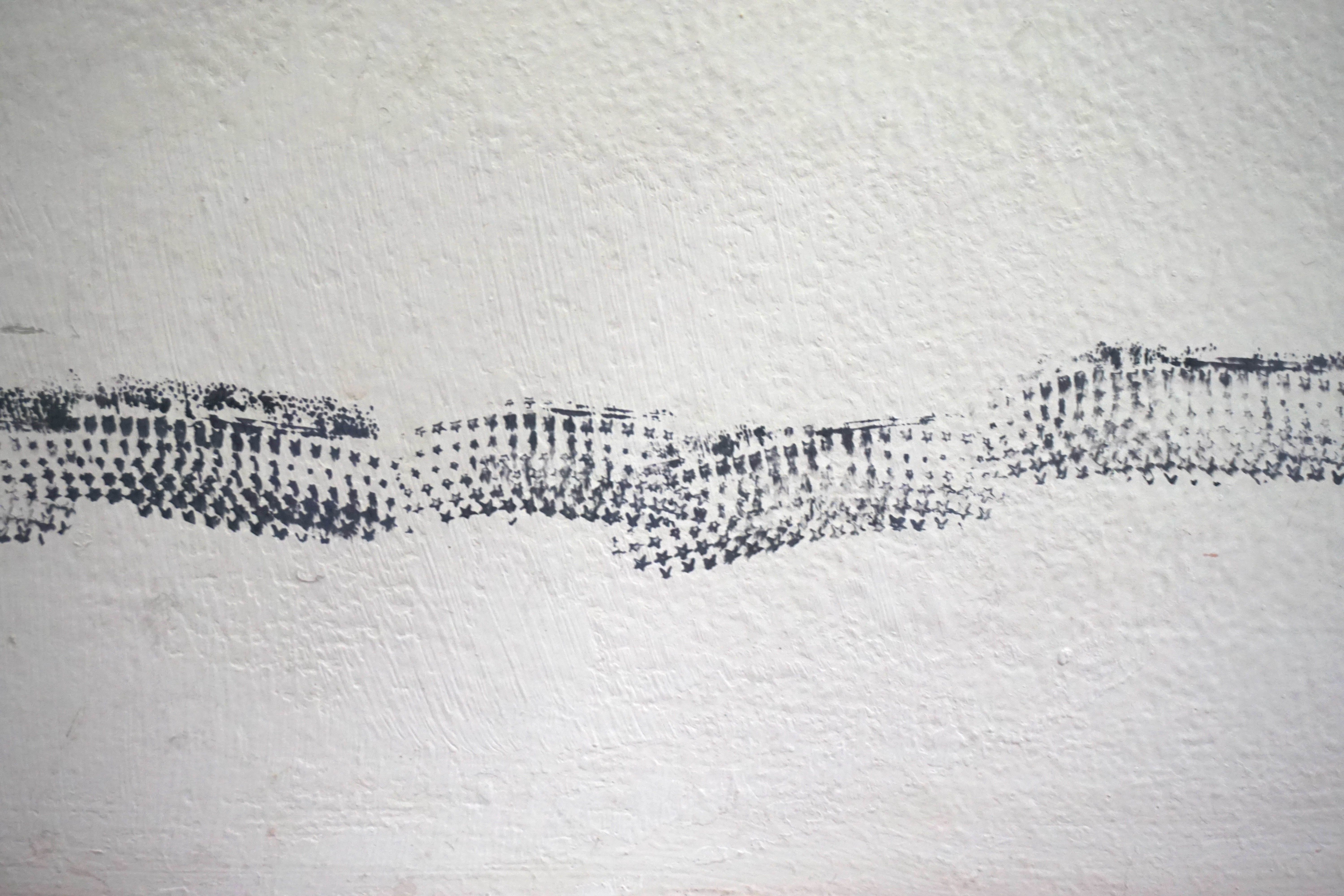 Band of black star prints on a white plaster wall