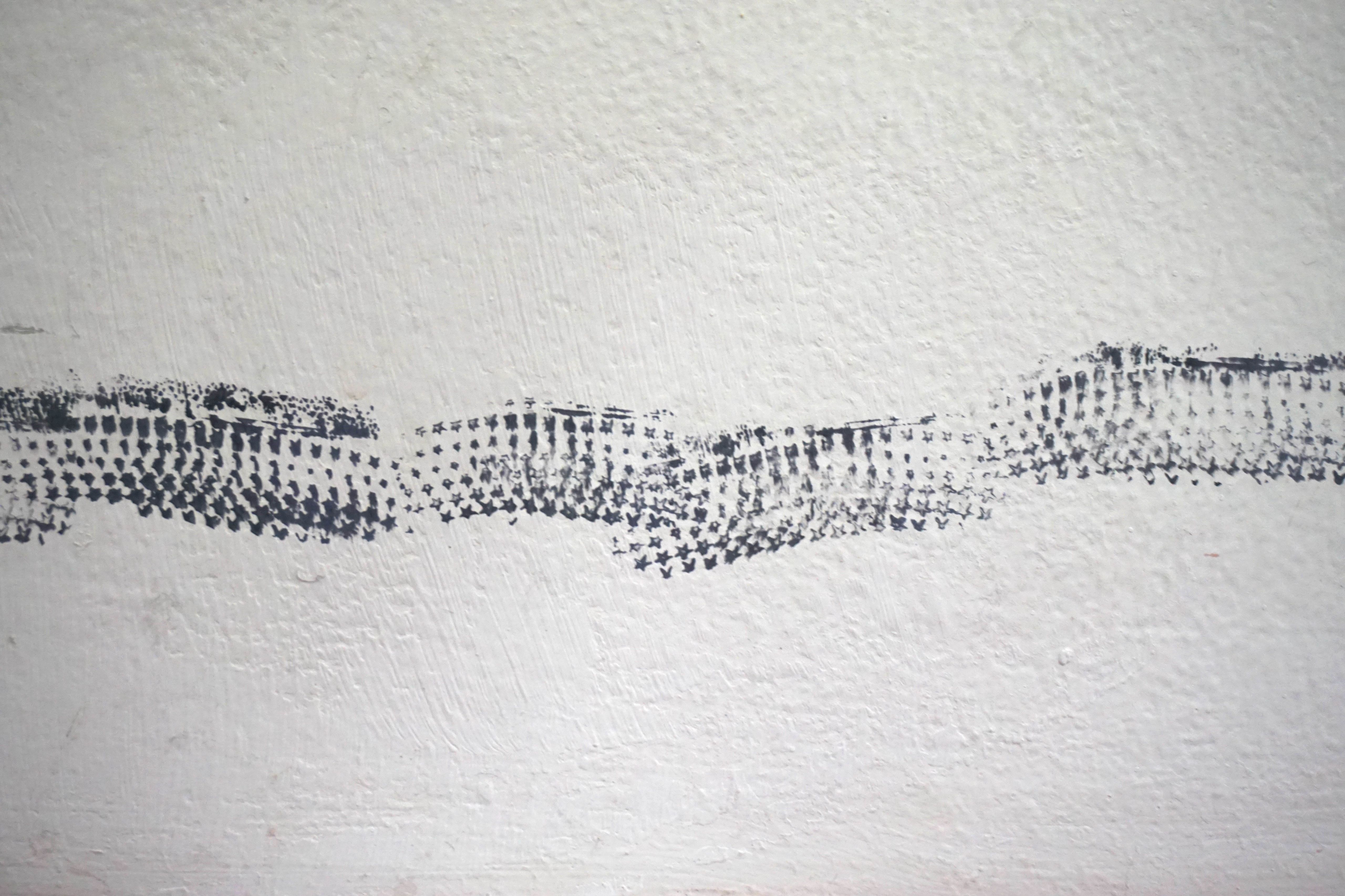 Band of black star prints on a white plaster wall