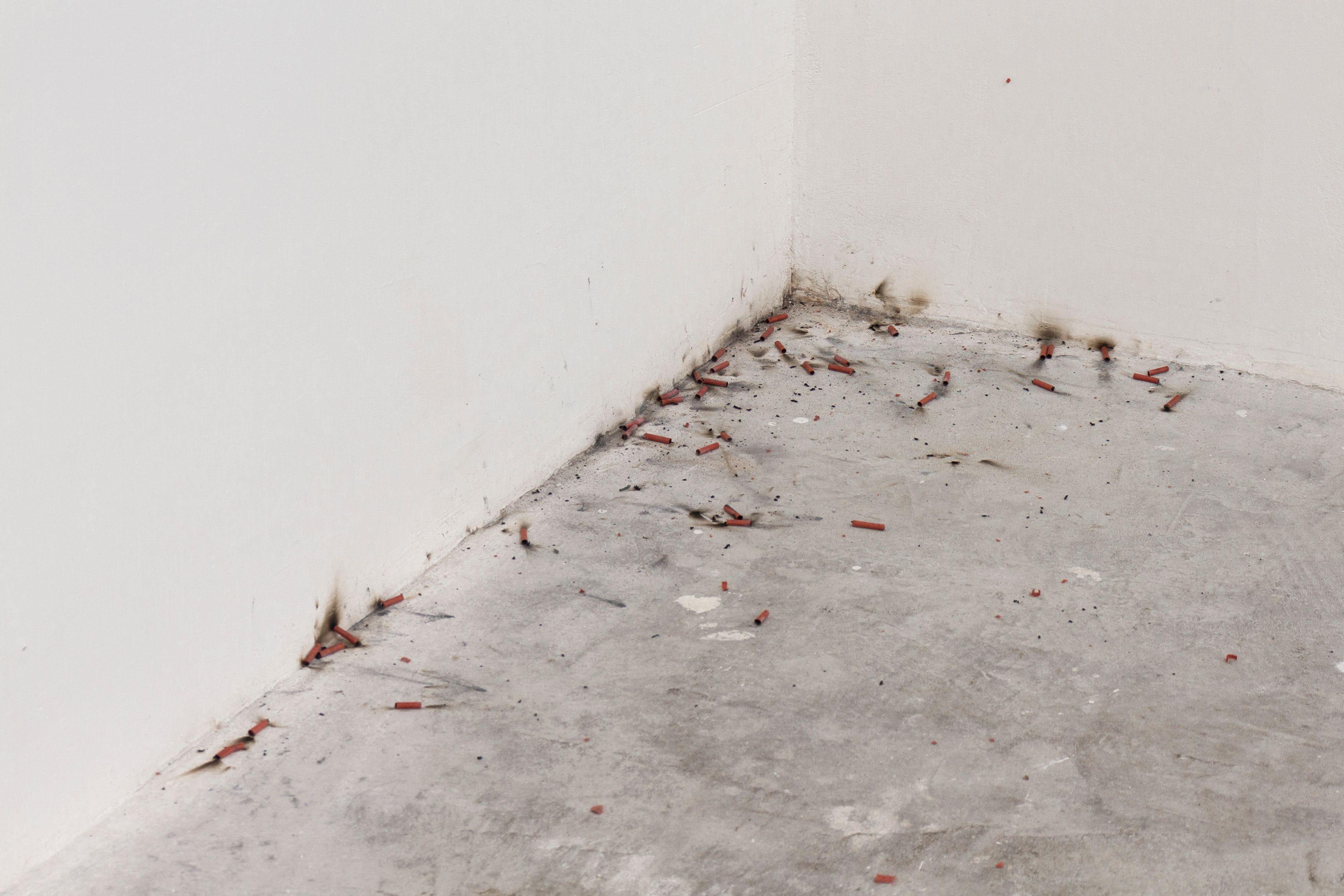 Burn traces in the corner where a white wall meets a concrete floor