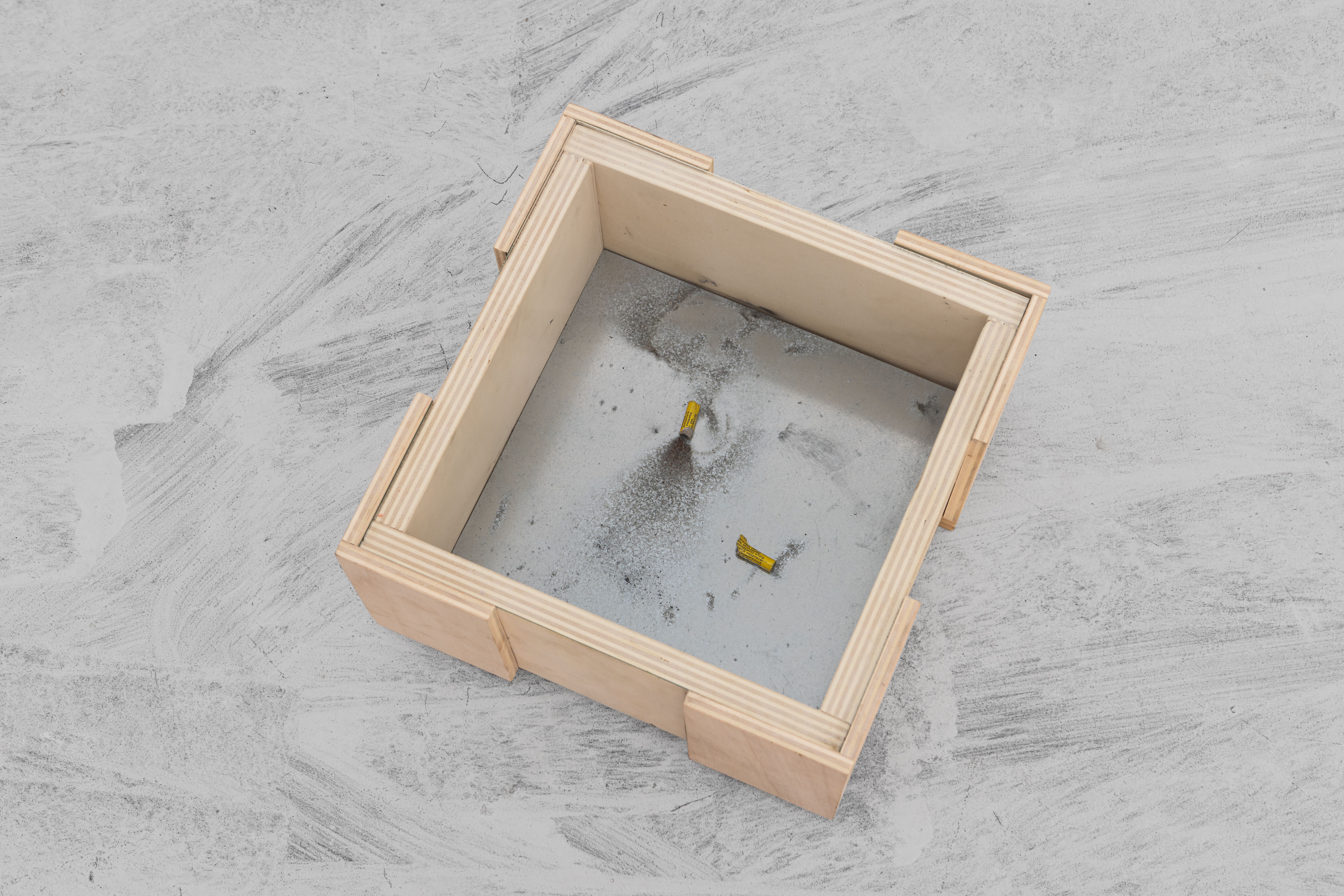 Wooden case seen from above, its glass bottom marked by an exploded firecracker