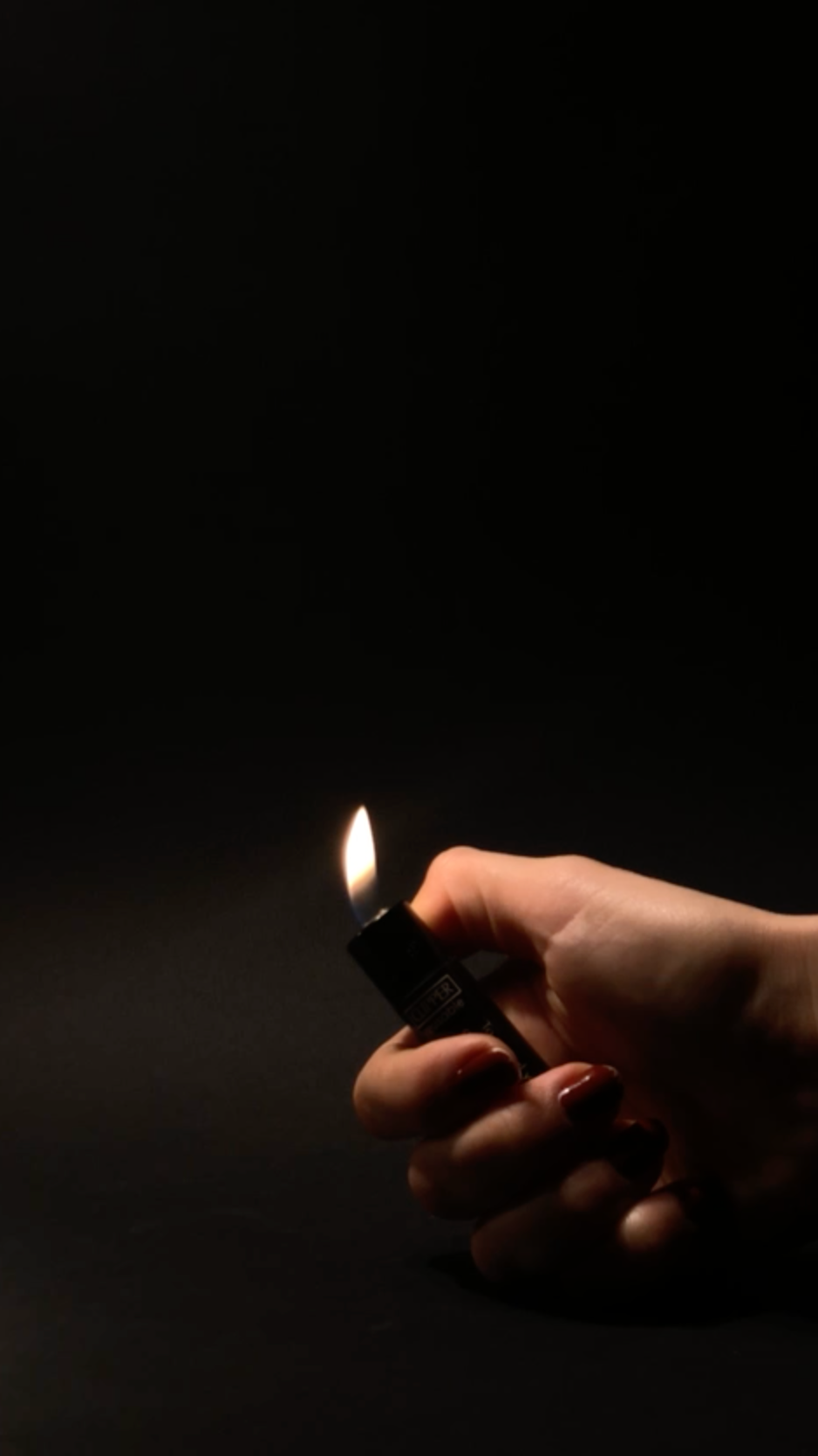 Hand lighting the black lighter in the dark