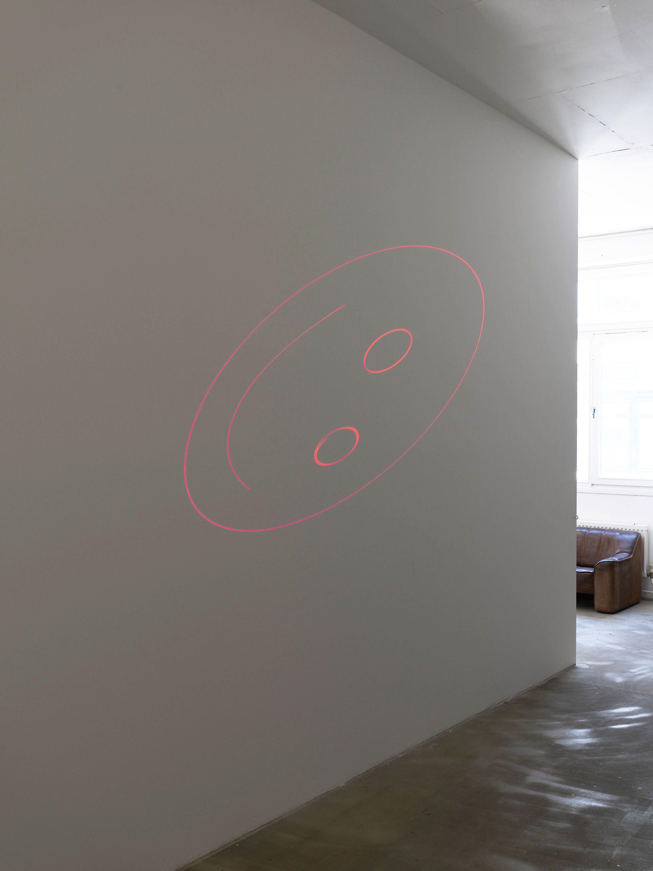 Red laser smiley projected on a white gallery wall
