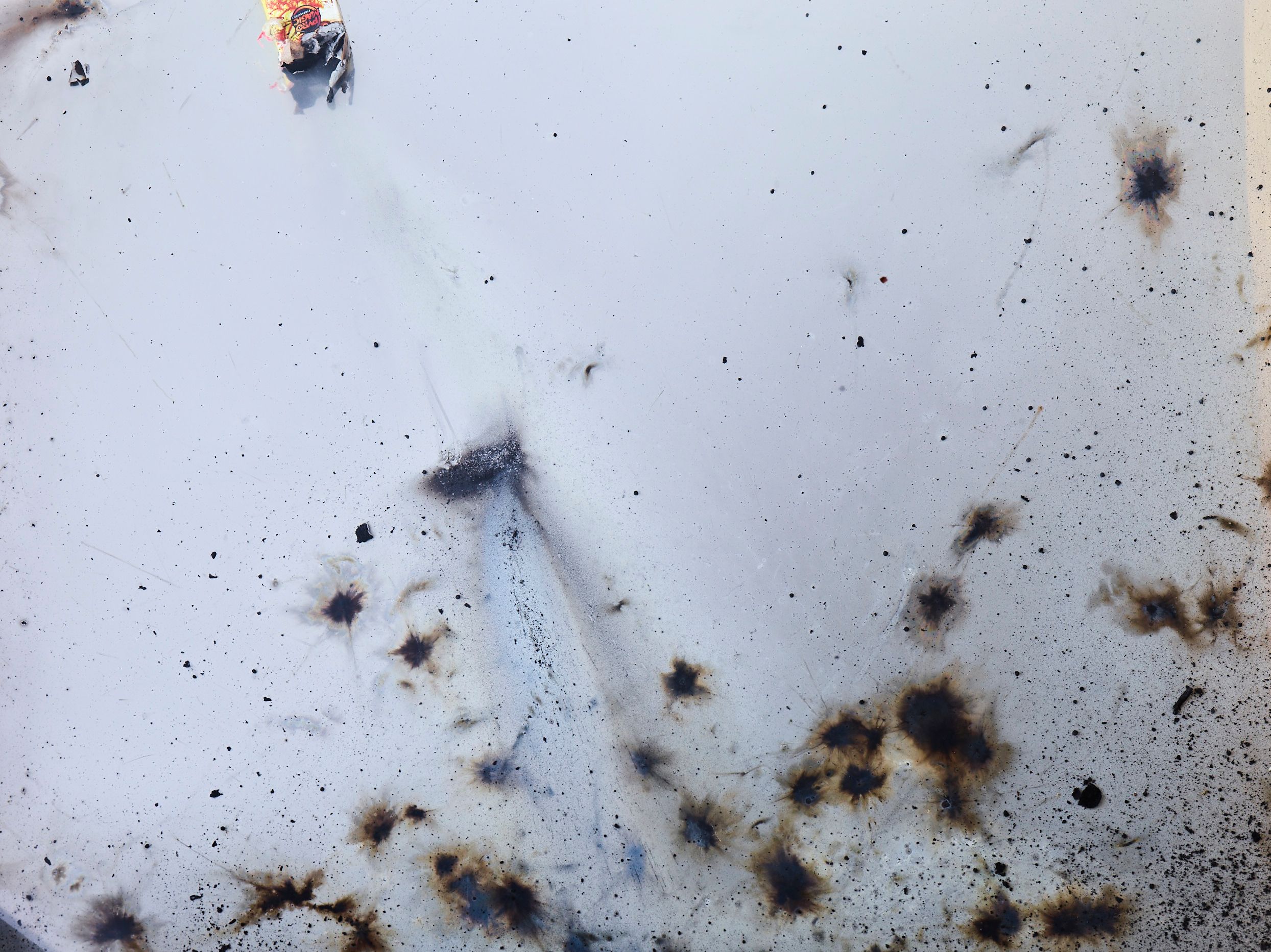 Close-up of soot bursts and a spent firecracker on a glass surface