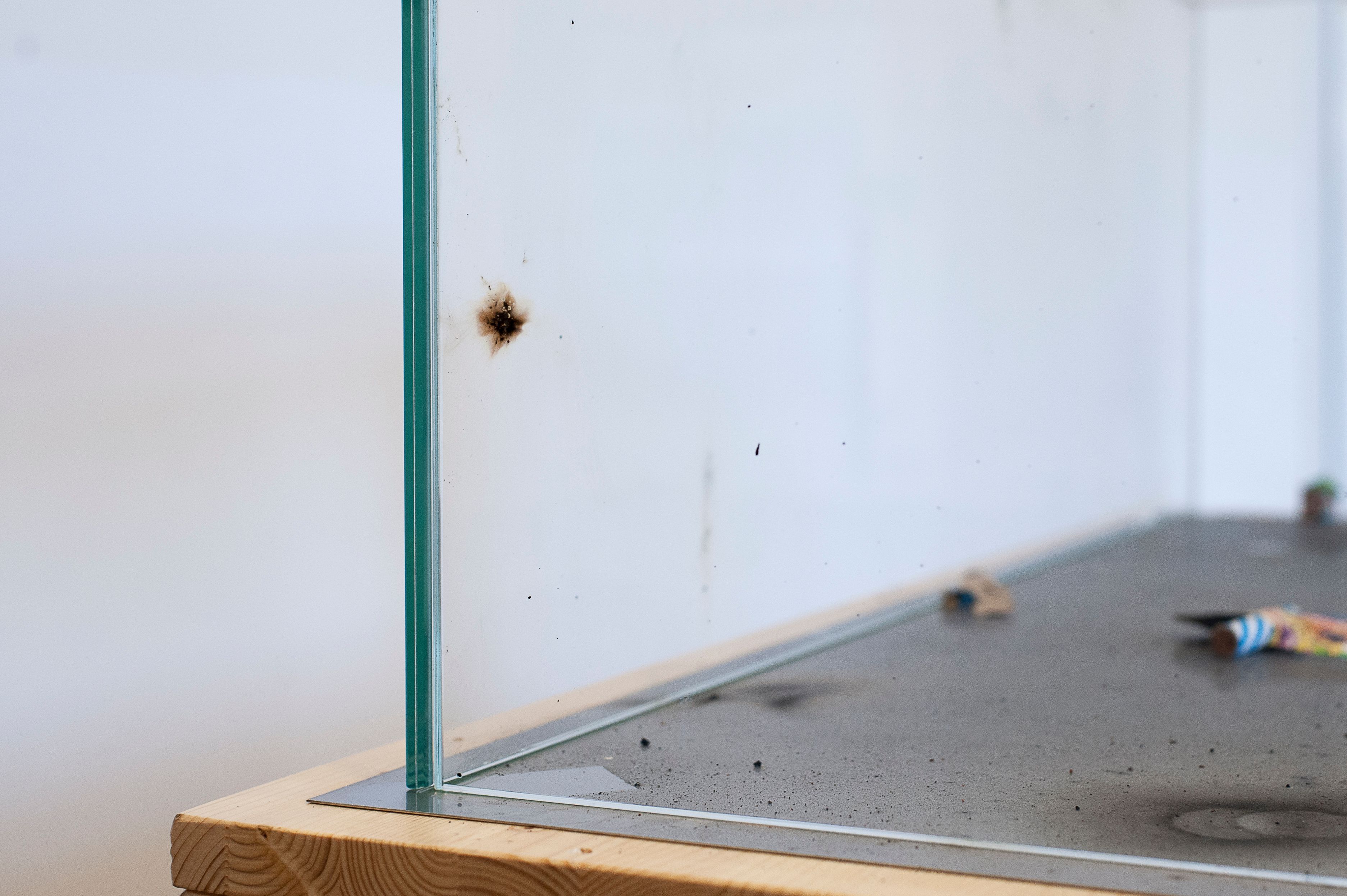 Detail of a burn mark on the glass case, with firecracker remains inside