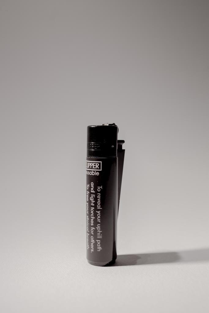 Black lighter printed with a short poem, standing on a grey background