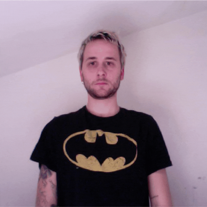 Animated gif of a man in a Batman T-shirt standing in front of a white wall
