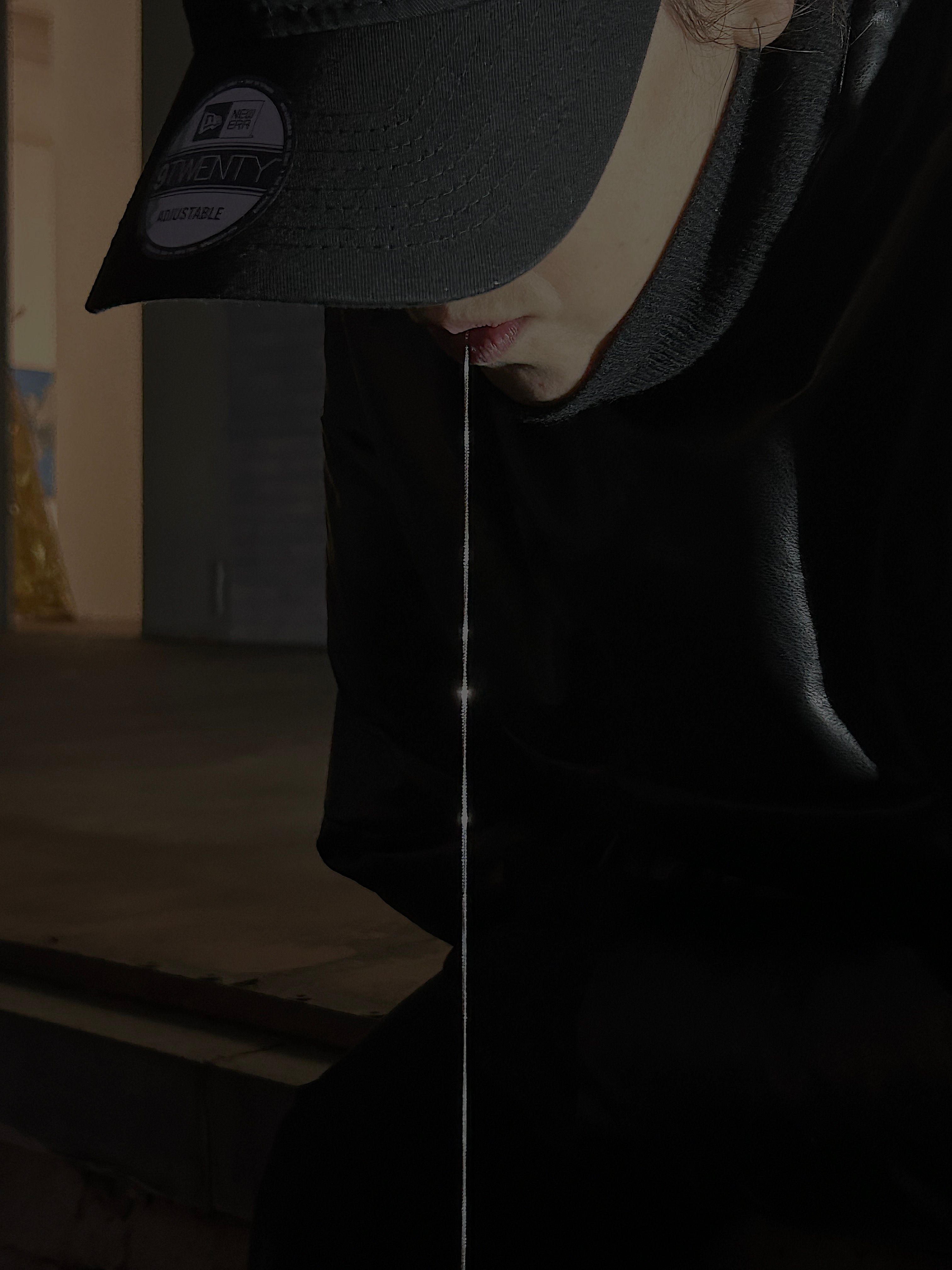 Close-up of a person in a cap with a silver chain hanging from the tongue