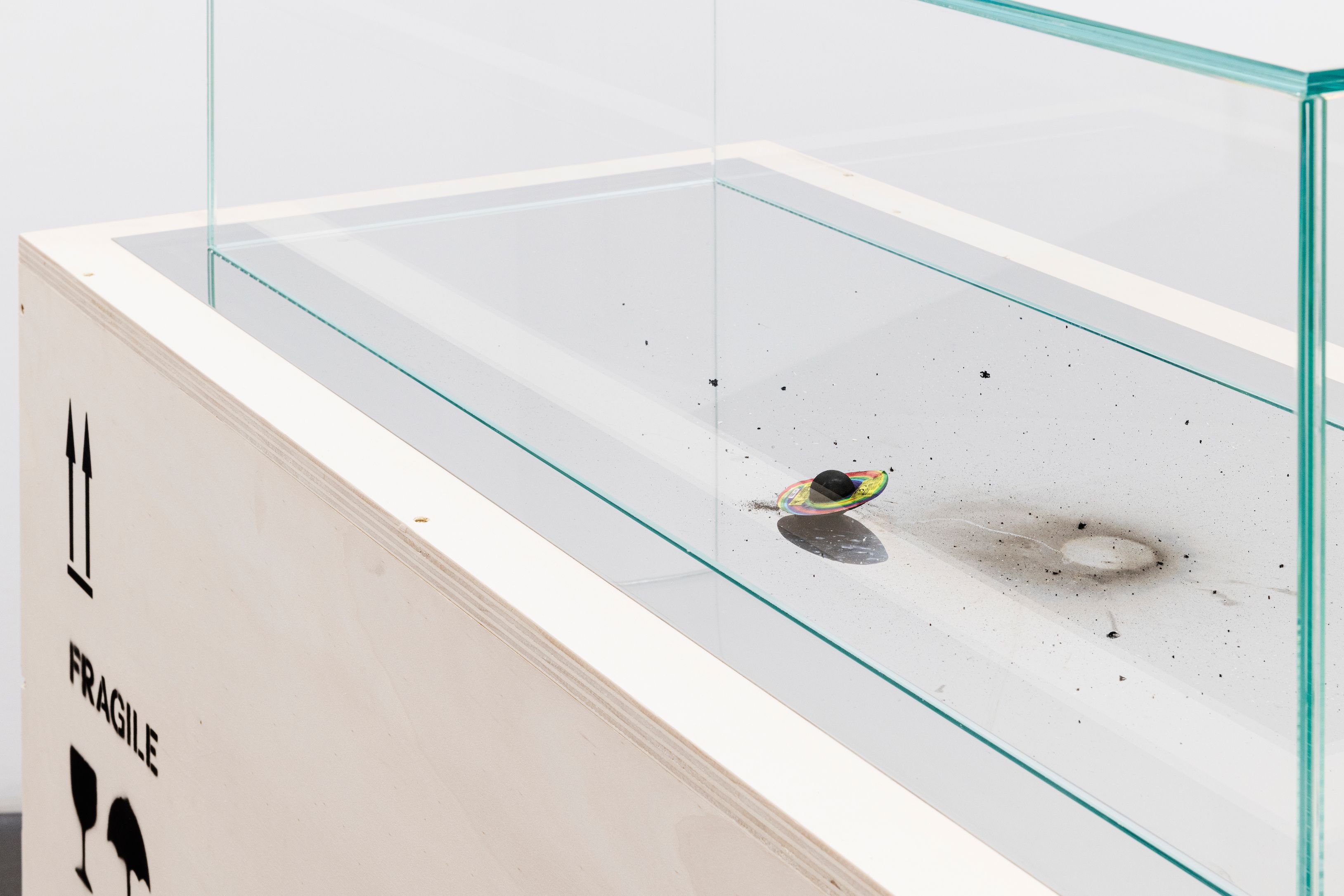Glass case on a wooden crate marked FRAGILE, with firecracker residue inside