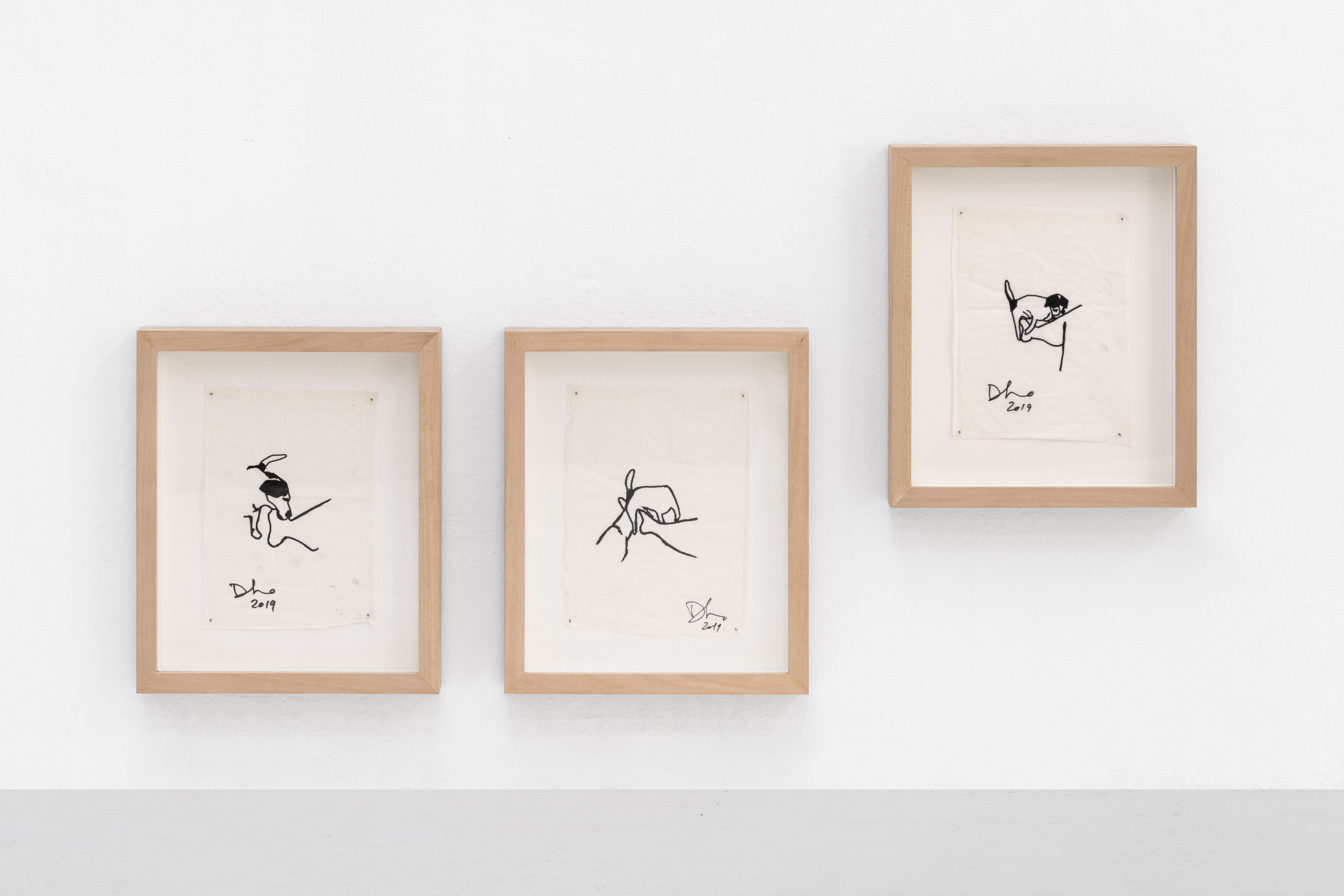 Three framed black ink drawings on a white wall